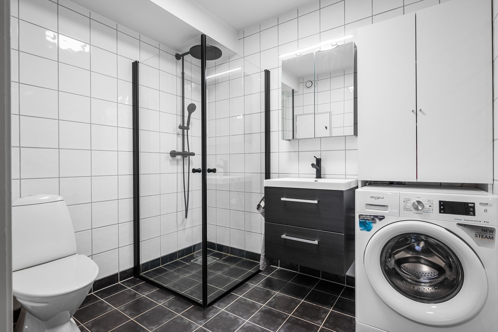 Badet er romslig og er innredet med et stilrent baderomsmøblement, dusjhjørne og toalett. Galleribilde