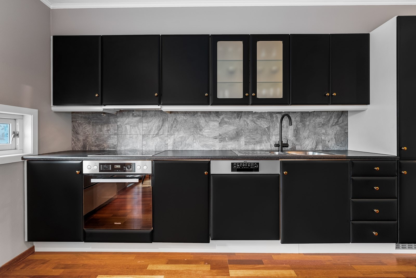 Kjøkkenet har en pen innredning med mørke fronter og godt med skap- og benkeplass som gir god arbeidsflyt. Galleribilde