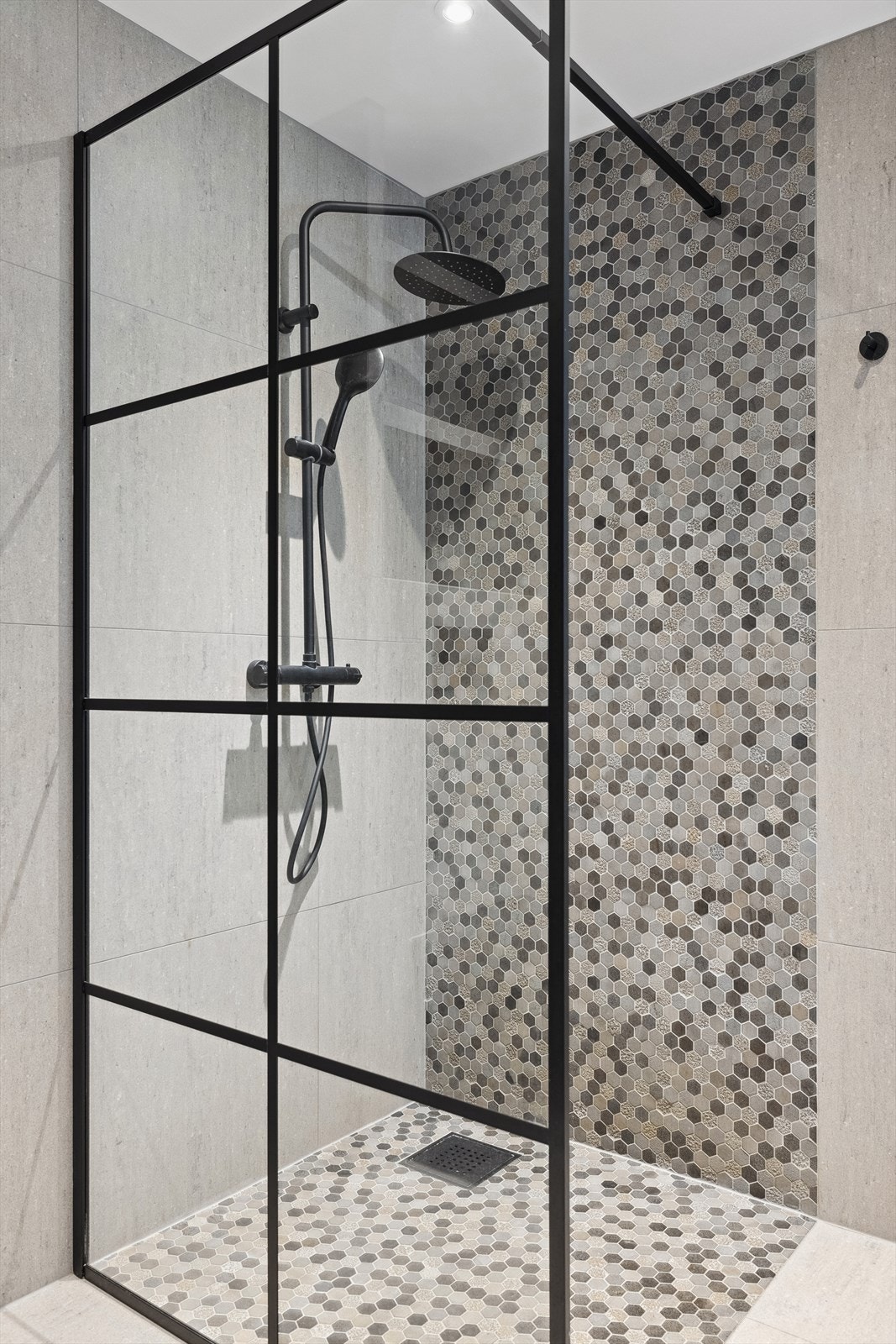 Rommet er innredet med egen dusjsone med glassvegg, baderomsinnredning med skuffeseksjon og bolleservant, belyst speil, egen nisje over toalett med hylle for oppbevaring, høyskap montert på vegg og vegghengt toalett. Galleribilde