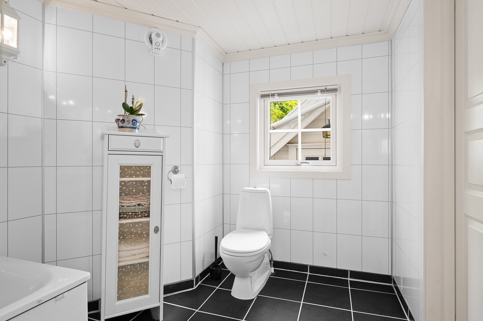 Bad med wc, badekar med dusjvegg og servant i pen innredning. Avtrekksvifte med fuktstyring. Galleribilde