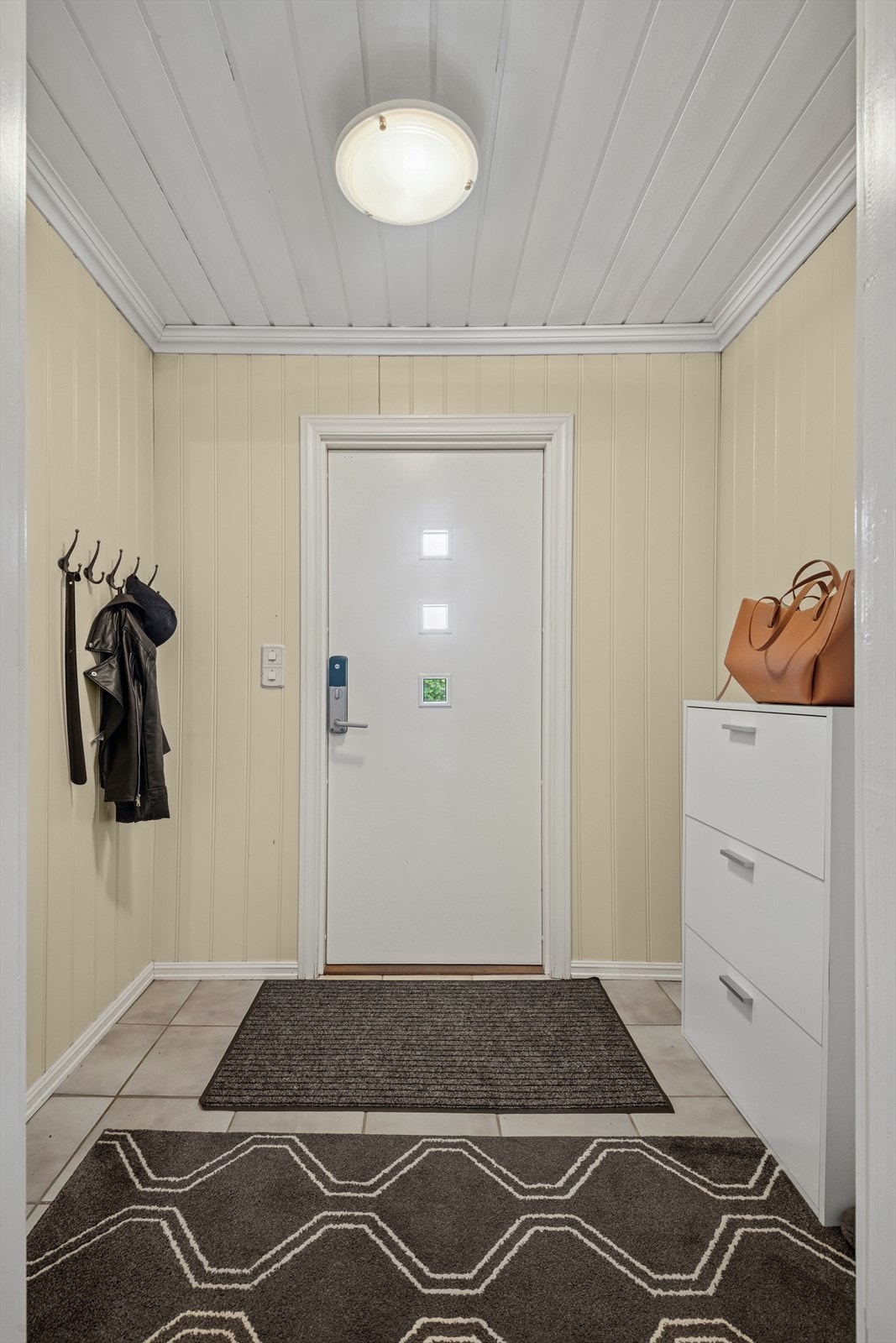 Lys og innbydende flislagt entré med god plass til å sette fra seg sko og henge fra seg yttertøy. Galleribilde