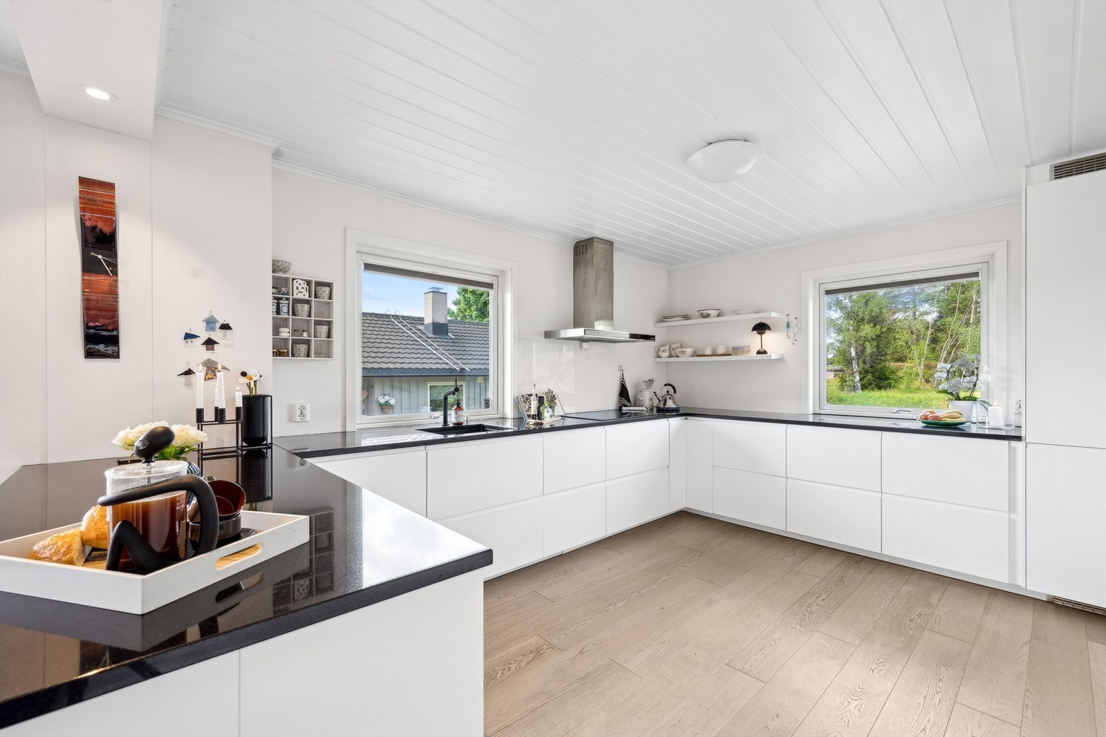 Lekkert kjøkken fra 2017 med slette fronter og benkeplate i stein, De store vindusflatene slipper inn god med naturlig lys. Galleribilde