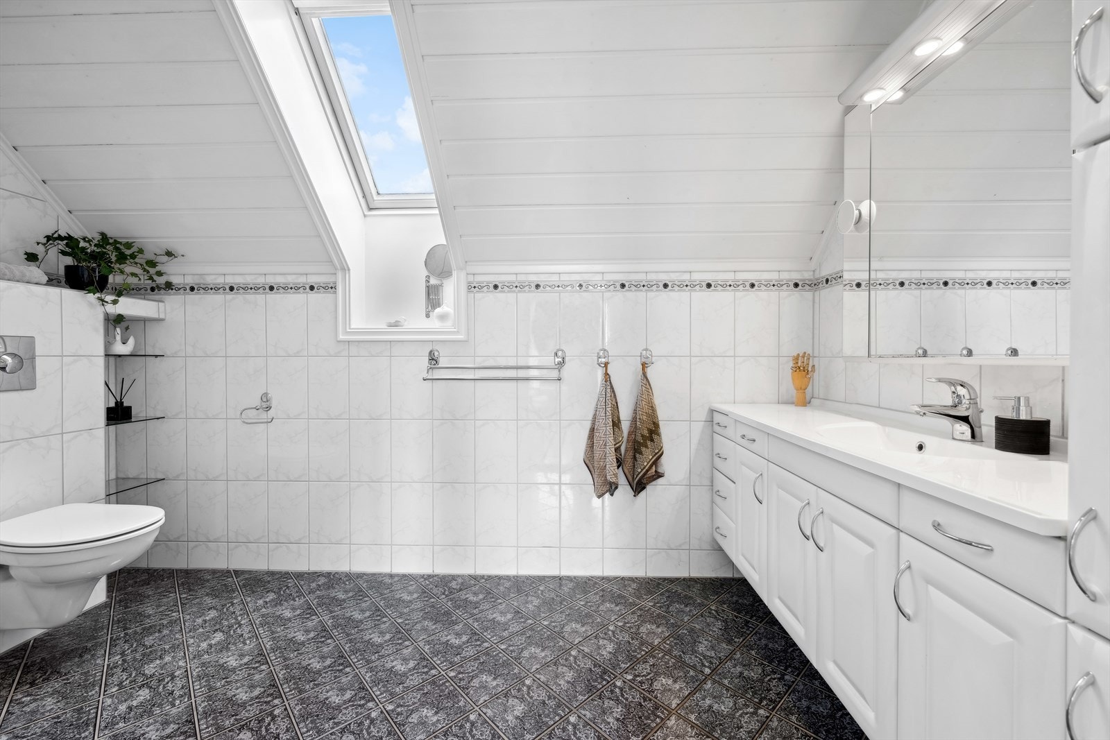 Badet har innredning med nedfelt servant, veggmontert toalett og dusjhjørne. Galleribilde