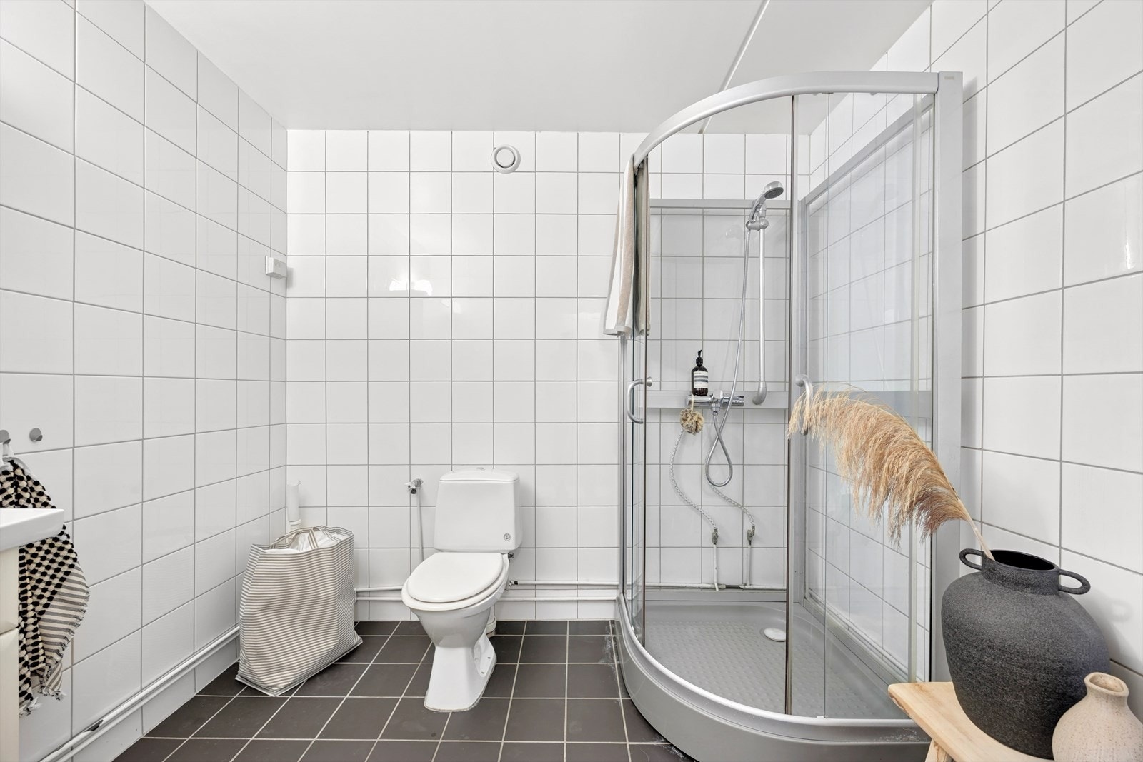 Badet er innredet med servantskap i hvit, glatt utførelse med heldekkende servant, overskap med speildører, wc og dusjkabinett. Det er i tillegg opplegg for vaskemaskin. Galleribilde