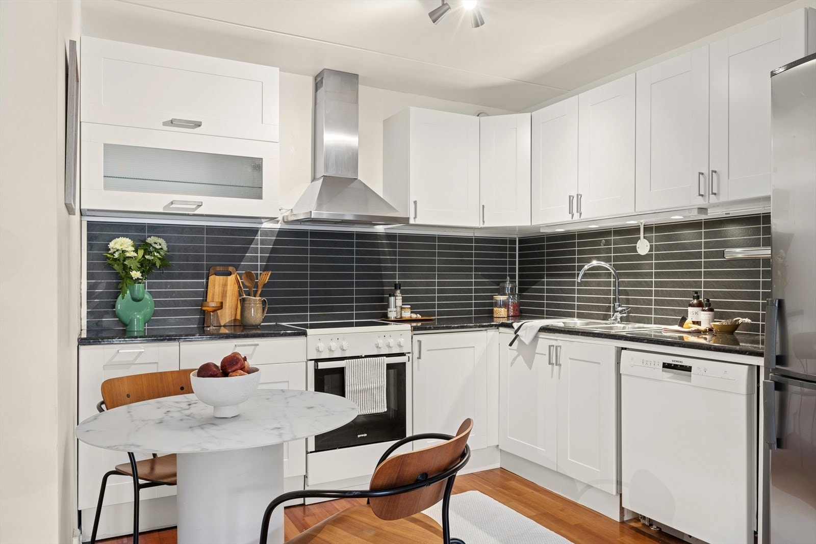 Kjøkkeninnredning med hvite, klassiske fronter og laminat benkeplate. Galleribilde