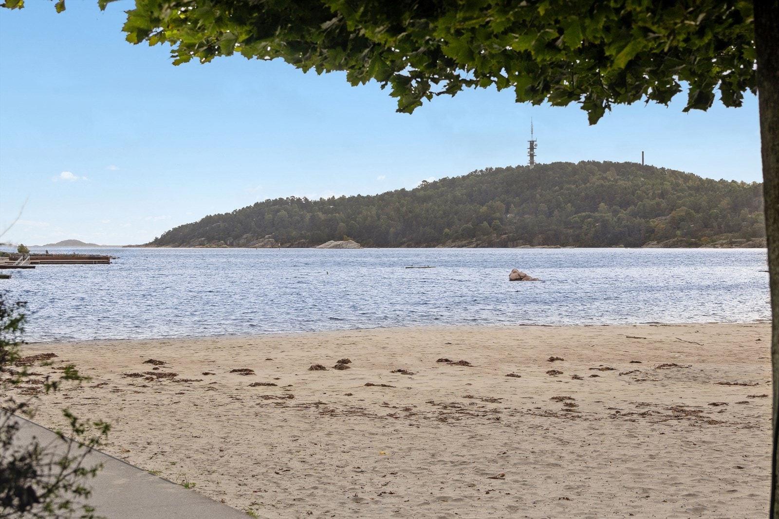 Stranden er kunstig anlagt med fin sand, sittegrupper, badebrygge og palmer - og er kjent for sin familievennlige, langgrunne utforming. Galleribilde