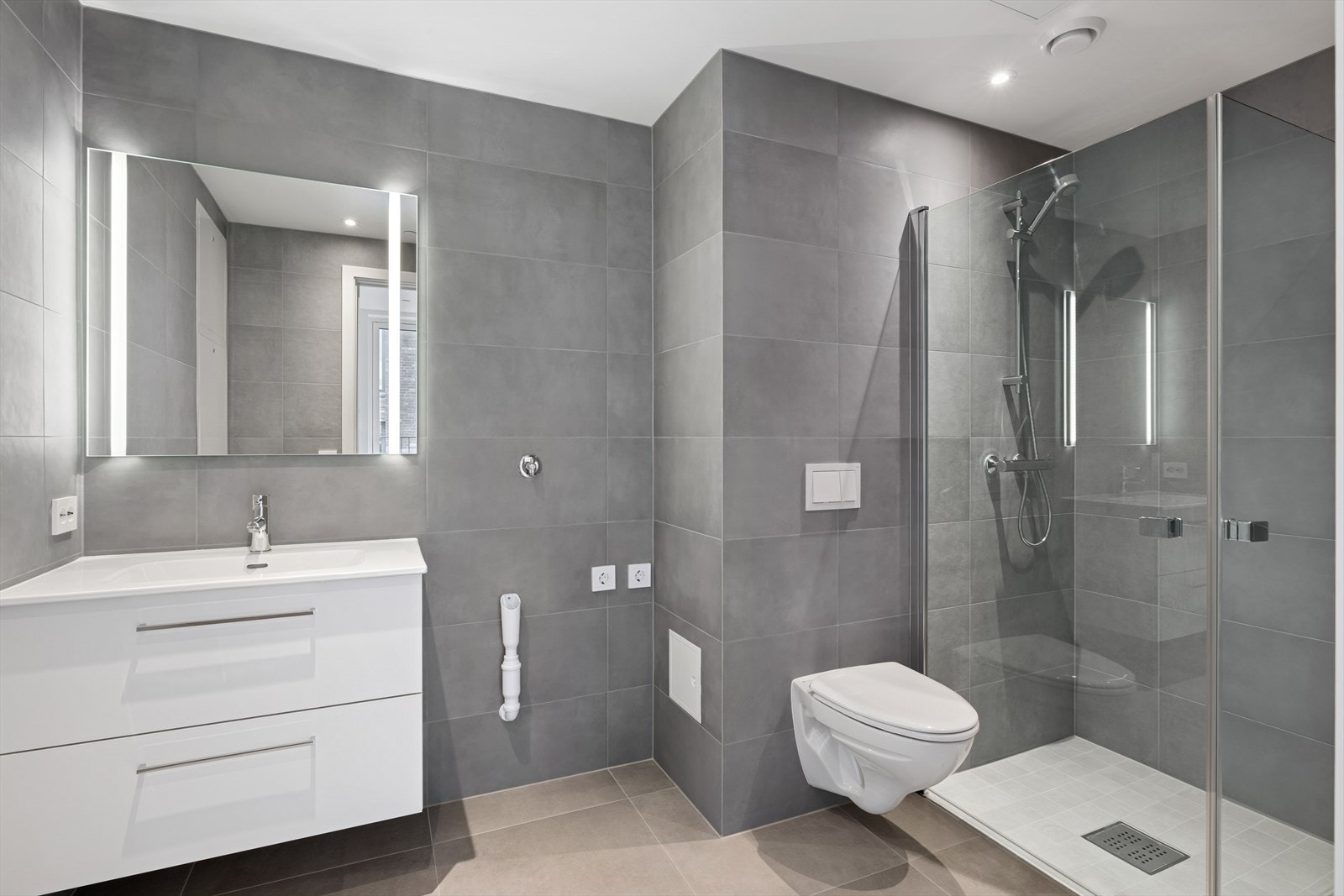 Badet er utstyrt med lys baderomsinnredning med gode skuffer, servant og speilskap med innebygget belysning. Galleribilde