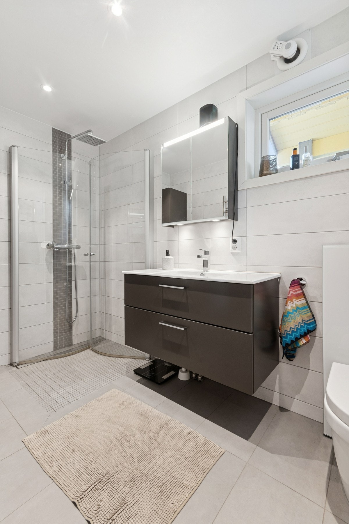 Badet i 1.etasje har flislagt gulv med elektriske varmekabler, samt fliser på vegger. Det er mekanisk avtrekk fra baderomsvifte. Galleribilde