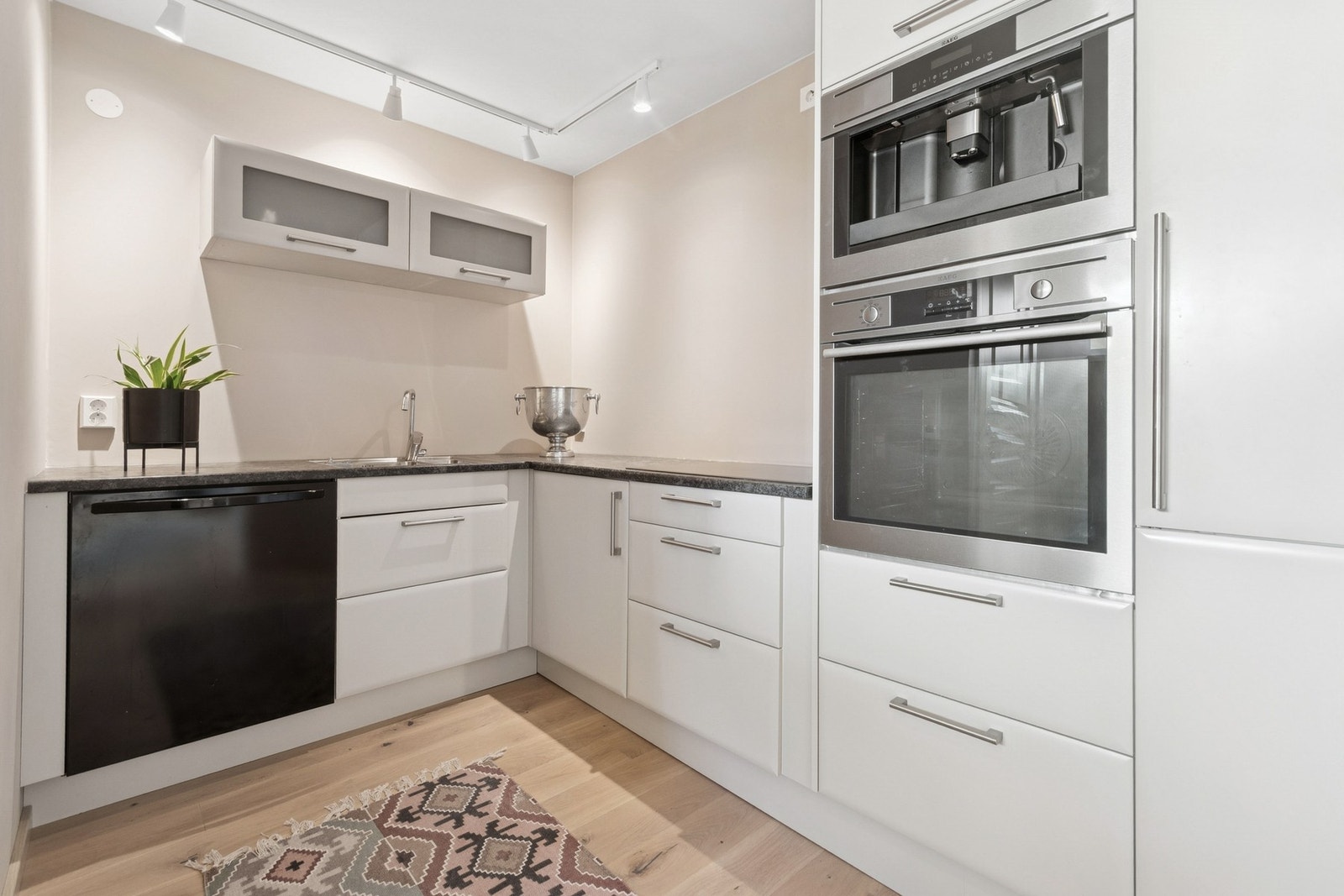 Kjøkken med Norema kjøkkeninnredning og benkeplate i laminat. Det er integrert platetopp, stekeovn, kaffemaskin og kjøleskap. Galleribilde