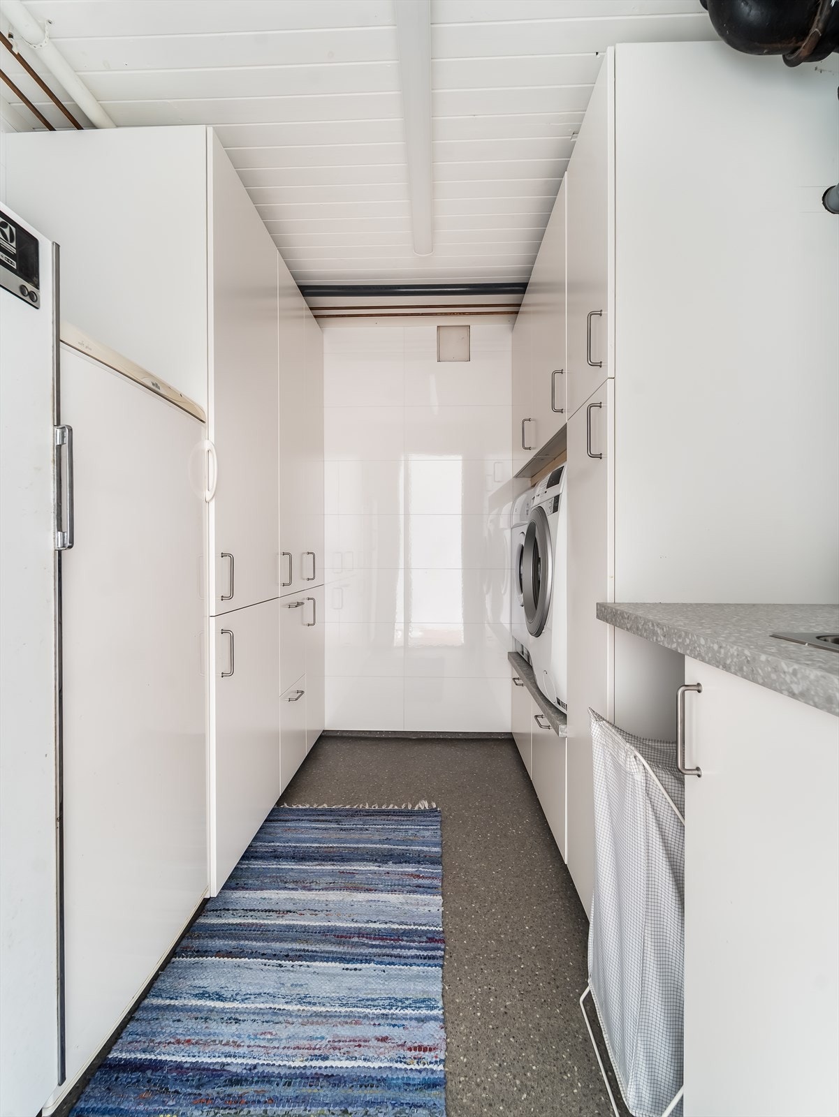 Praktisk vaskerom med mye garderobeskap og opphøyd løsning til vaskemaskin/tørketrommel. Galleribilde