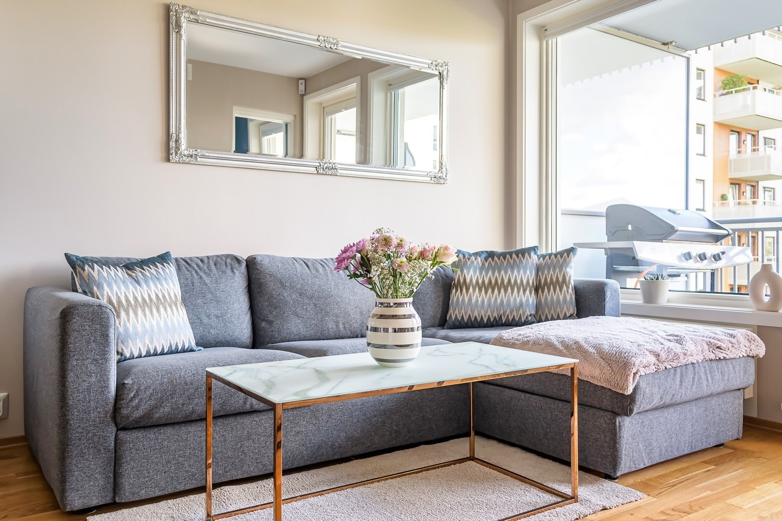Sofasonen fremstår som lun og innbydende, med flott utsyn og en naturlig forlengelse av leilighetens harmoniske stil. Galleribilde