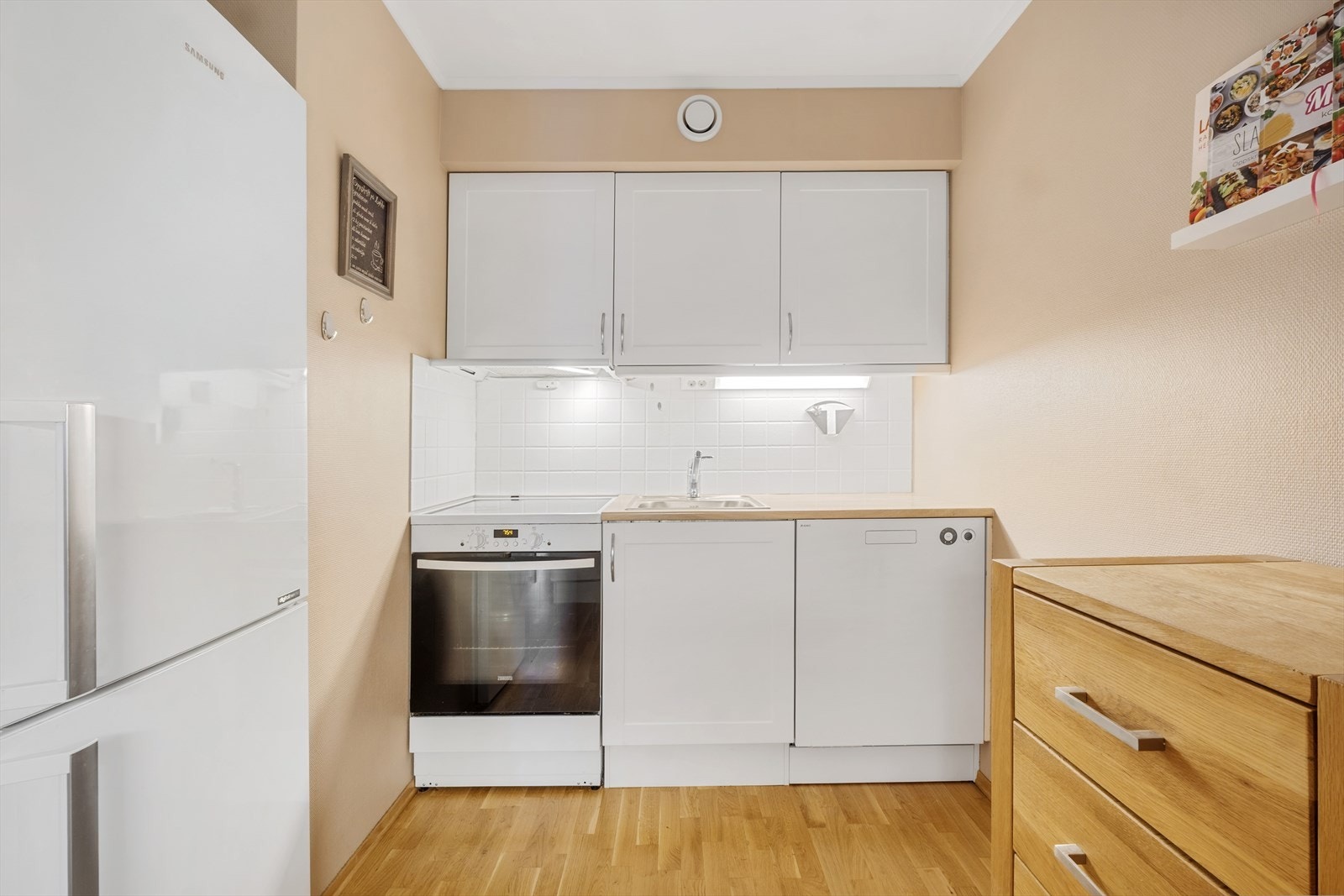 Kjøkkeninnredning av typen Norema med eik fronter, normalt utbygget med skapplass. Opplegg for oppvaskmaskin. Galleribilde