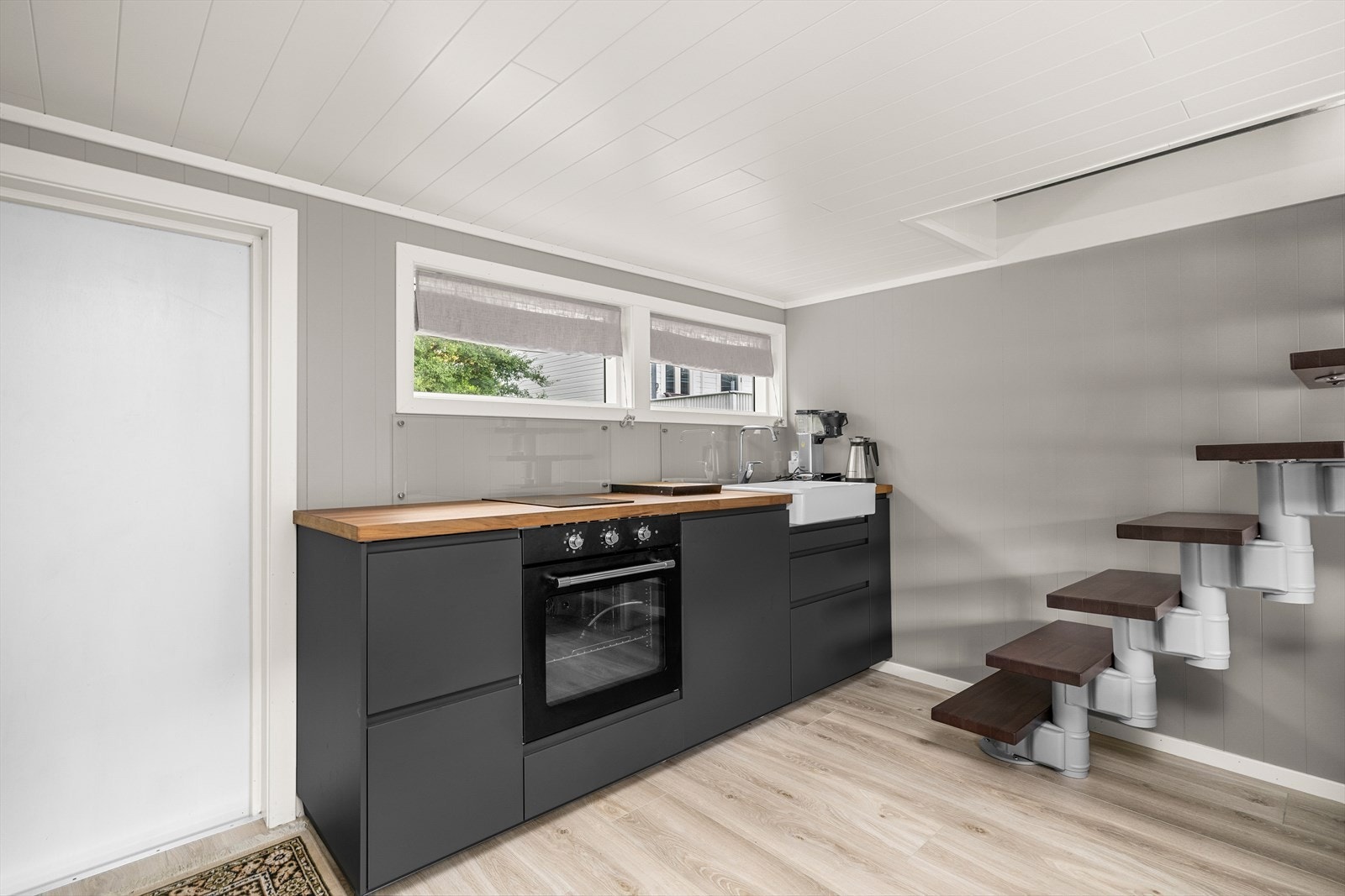 I uthuset finner man et moderne kjøkken med sorte, matte fronter og integrerte hvitevarer Galleribilde