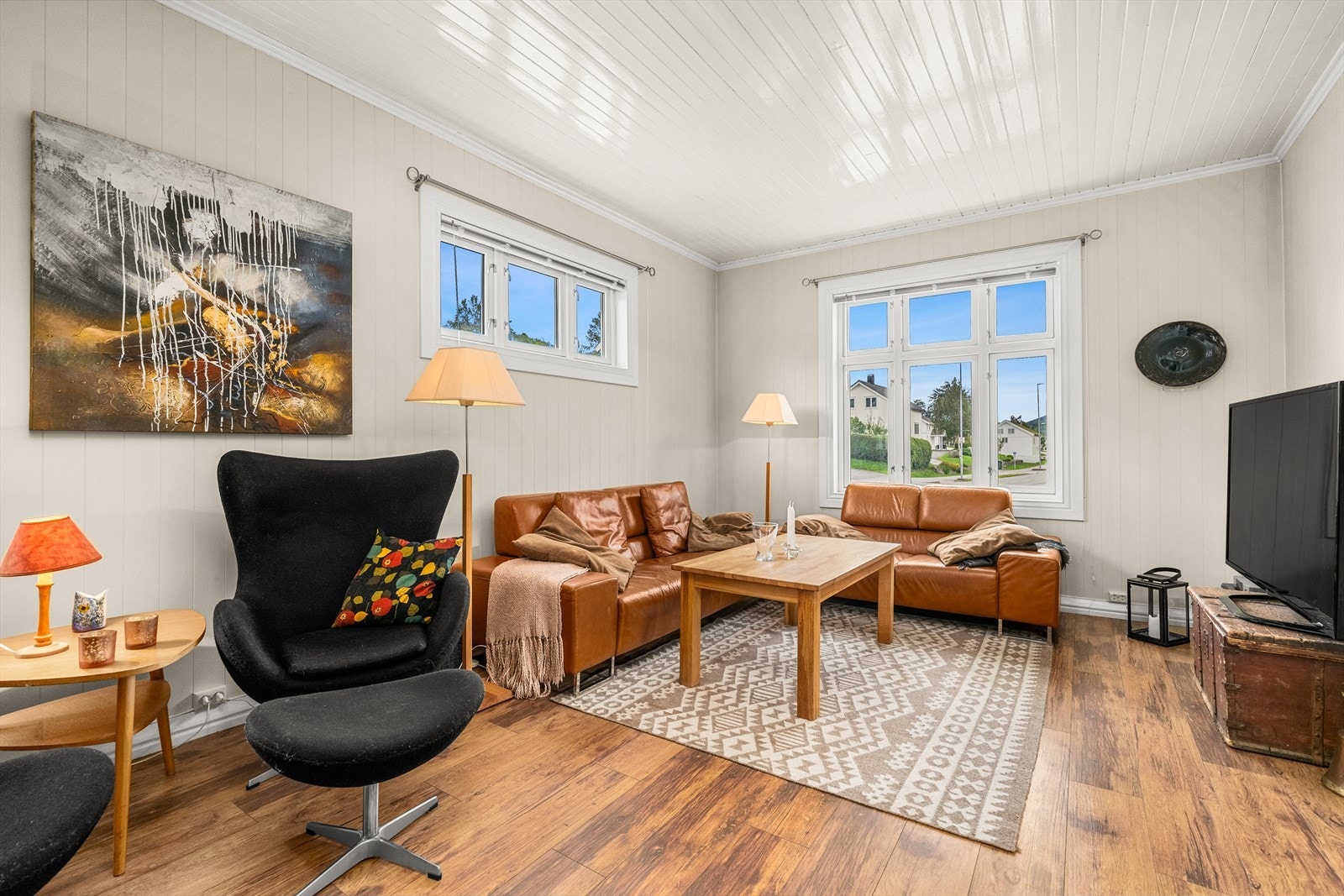 Flere store vindusflater på stuen som slipper inn rikelig med naturlig lys Galleribilde