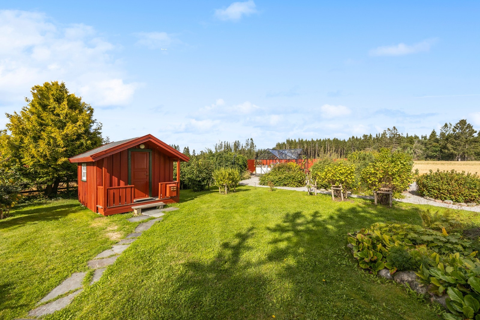 Tunet er pent opparbeidet med blomsterbed, busker, plen og grus-/steinstier Galleribilde