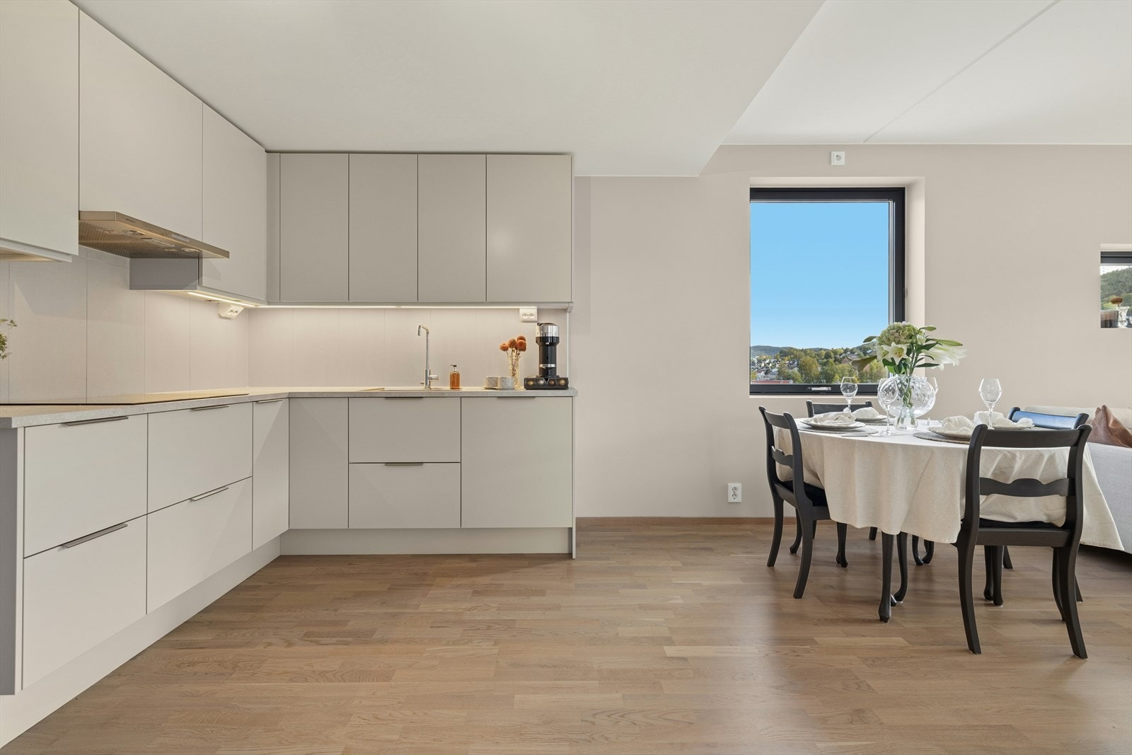 Kjøkkenet er moderne med glatte fronter og laminat benkeplate, fliser over benk, samt integrerte hvitevarer som inkluderer kjøl/frys, oppvaskmaskin, komfyr, induksjonstopp og stekeovn Galleribilde