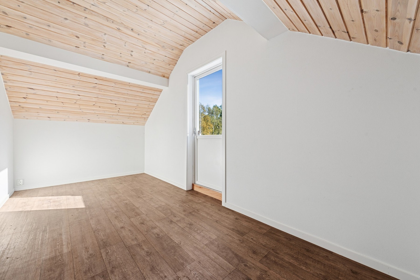 Det andre soverommet i etasjen har lyse vegger og skråtak med panel, som gir en lun atmosfære. Rommet har også utgang til en liten balkong! Et hyggelig sted å trekke ut for frisk luft. Galleribilde