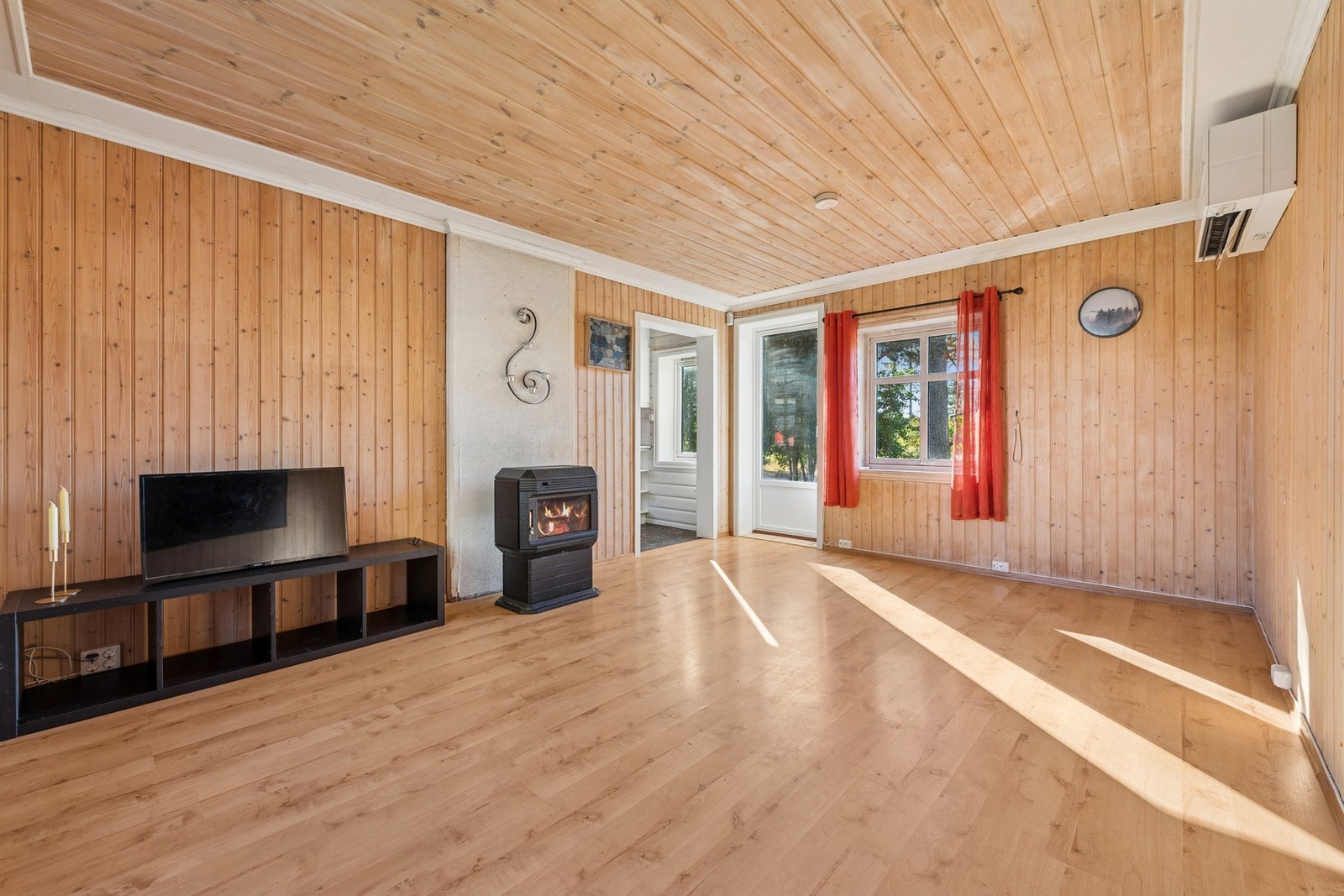 Stuen har direkte utgang til uteområdet og store vindusflater som slipper inn godt med lys. Her finner du både varmepumpe og vedovn som gir fleksible oppvarmingsmuligheter gjennom året. Galleribilde