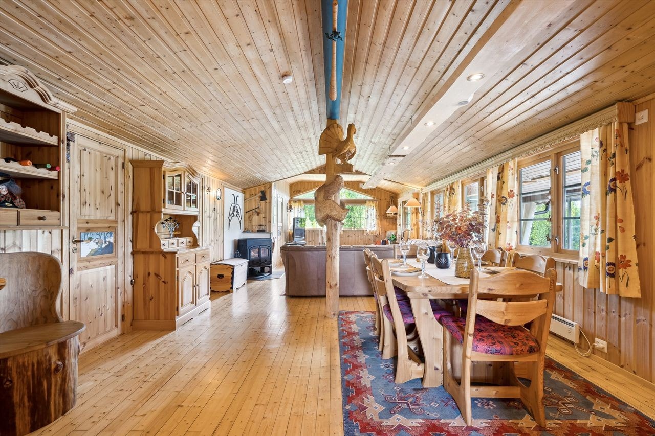 Stua har skrå himling, panelte vegger og god plass til både sofagruppe og spisebord. Galleribilde