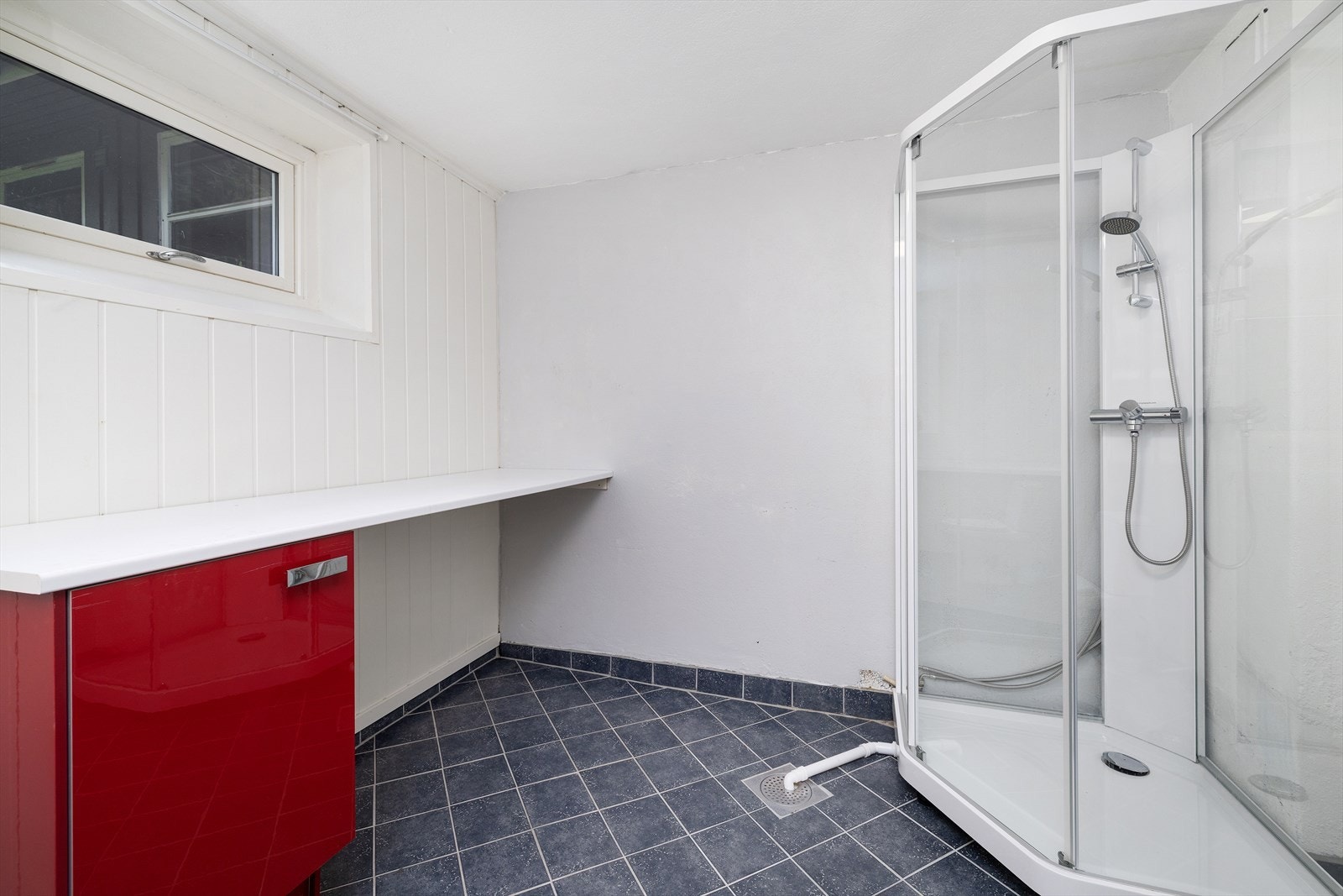 Rommet er innredet med dobbelt servant i underskap, veggmontert toalett, dusjkabinett og opplegg for vaskemaskin. Galleribilde