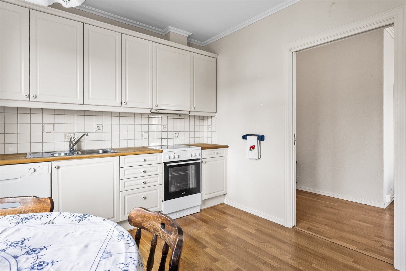 Kjøkkenet er både funksjonelt og innbydende, med parkett på gulvet som gjør det varmt og hjemmekoselig. Veggene er kledd med malt glassfiberstrie, mens taket er malt i en lys og nøytral farge som gir rommet et rent og tidløst preg. Galleribilde