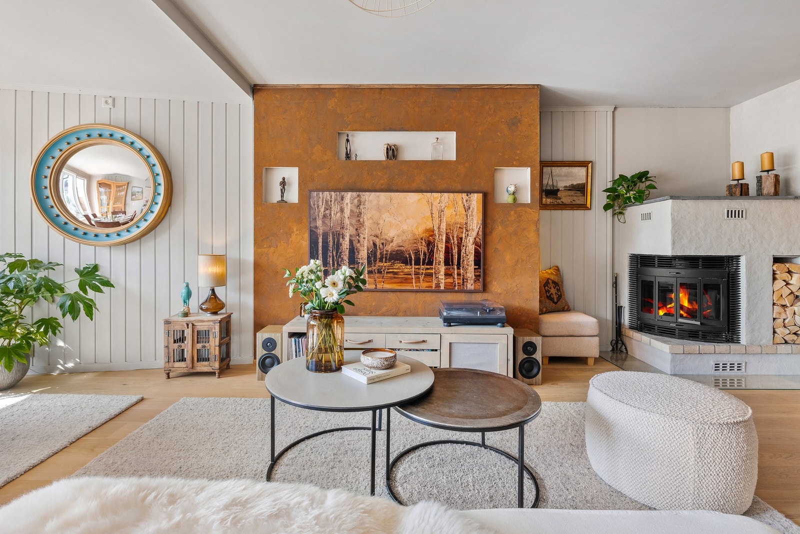 Det er bygget en smart tv-vegg med innbygget lysnisjer, skjult kabelopplegg, bokhylle og sitteplass på siden Galleribilde