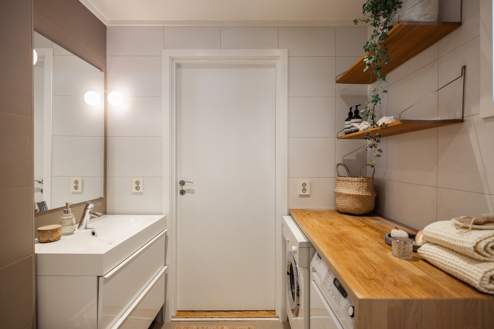 Baderomsinnredning med servantskap med skuffer og heldekkende servant, stort veggspeil samt integrert badekar med hånddusj og regndusj. Galleribilde