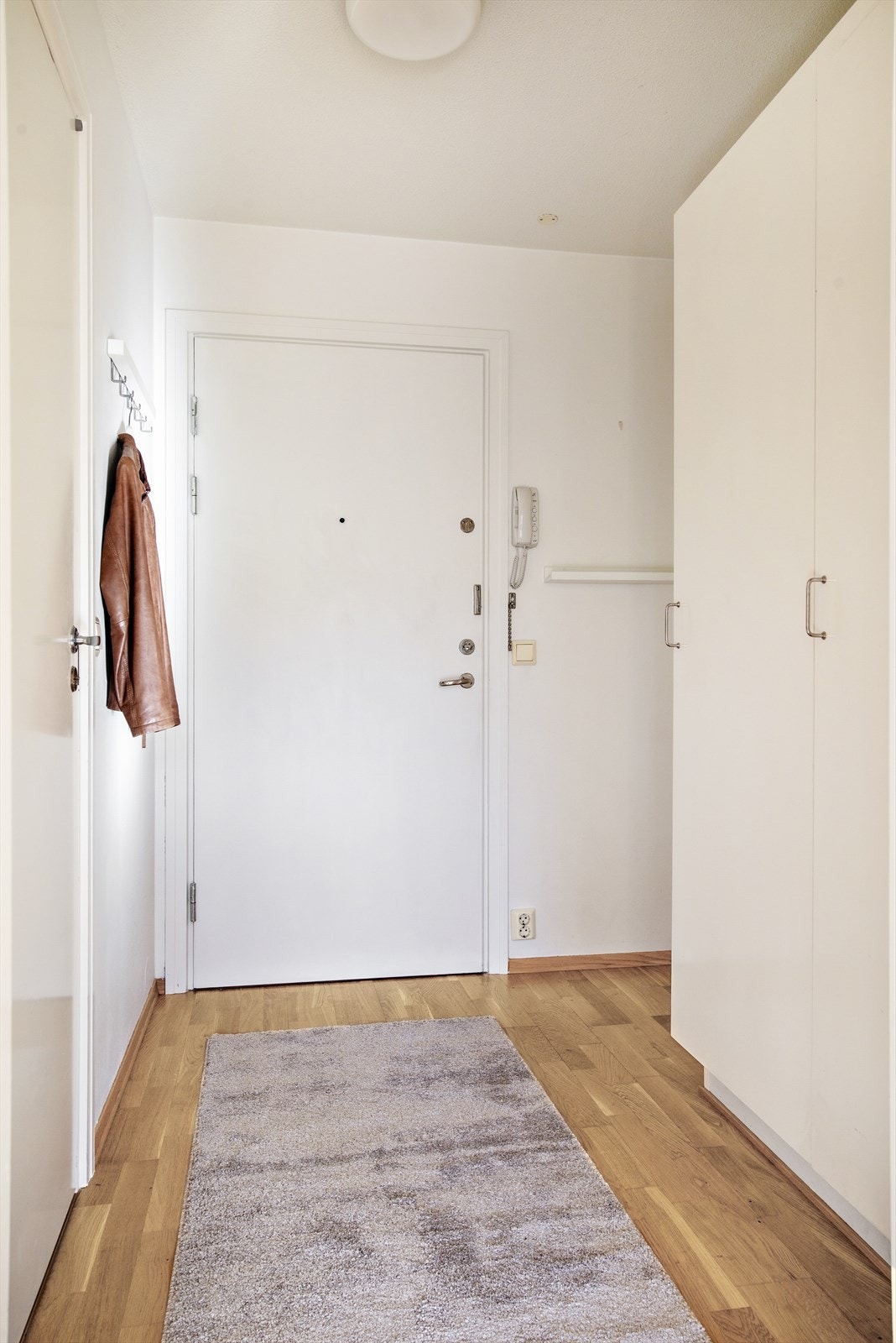 Leiligheten har en praktisk entré med parkett på gulv, malte overflater på vegger og himling. Det er plass til oppbevaring i garderobeskap og oppheng av jakker langs veggen. Galleribilde