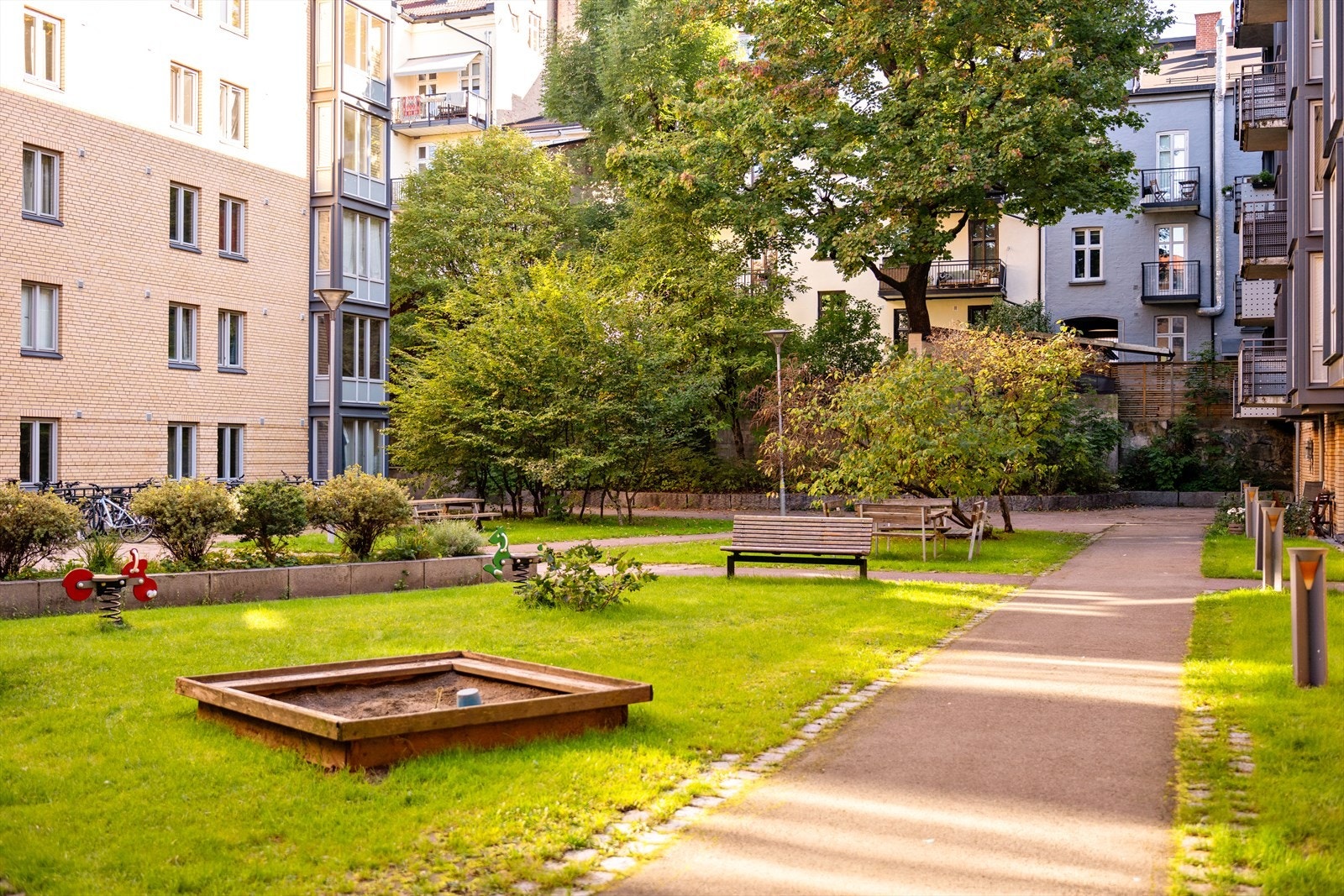 Pent opparbeidet gårdsrom med sitteplasser og lekeplass. Galleribilde