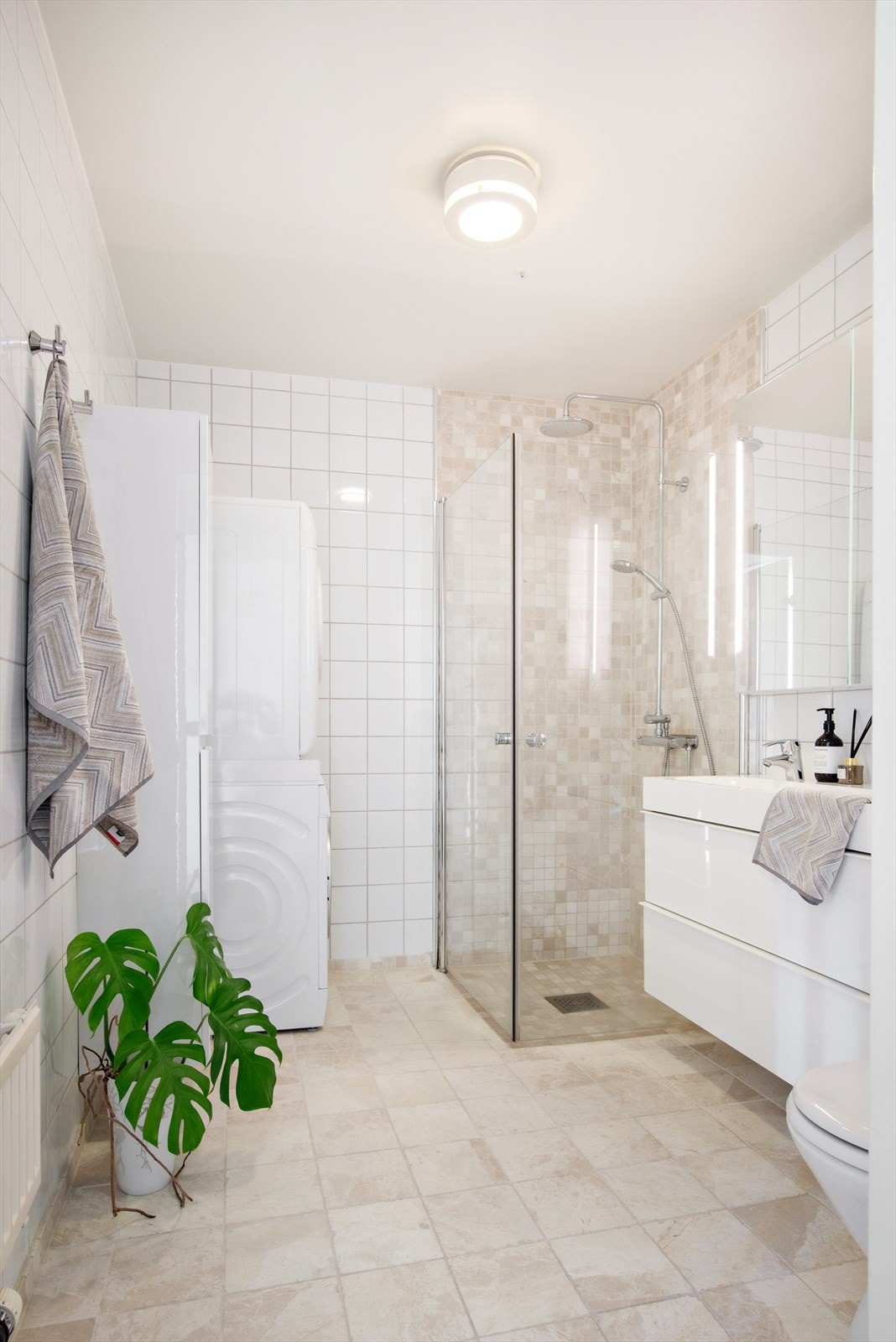 Pent og funksjonelt bad med fliser på både gulv og vegger. Det er opplegg for både vaskemaskin og tørketrommel, noe som gjør rommet praktisk i hverdagen. Badet har mekanisk avtrekk og oppvarming via radiator plassert ved døren. Galleribilde