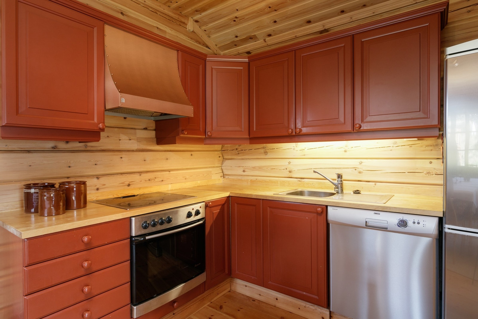 Kjøkkeninnredning i hovedhytten med røde profilerte fronter og heltre benkeplate Galleribilde