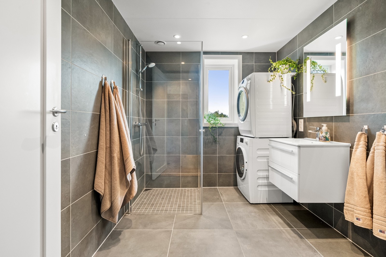 Dette moderne badet er utstyrt med dusjhjørne med glassvegg og flislagte gulv Galleribilde