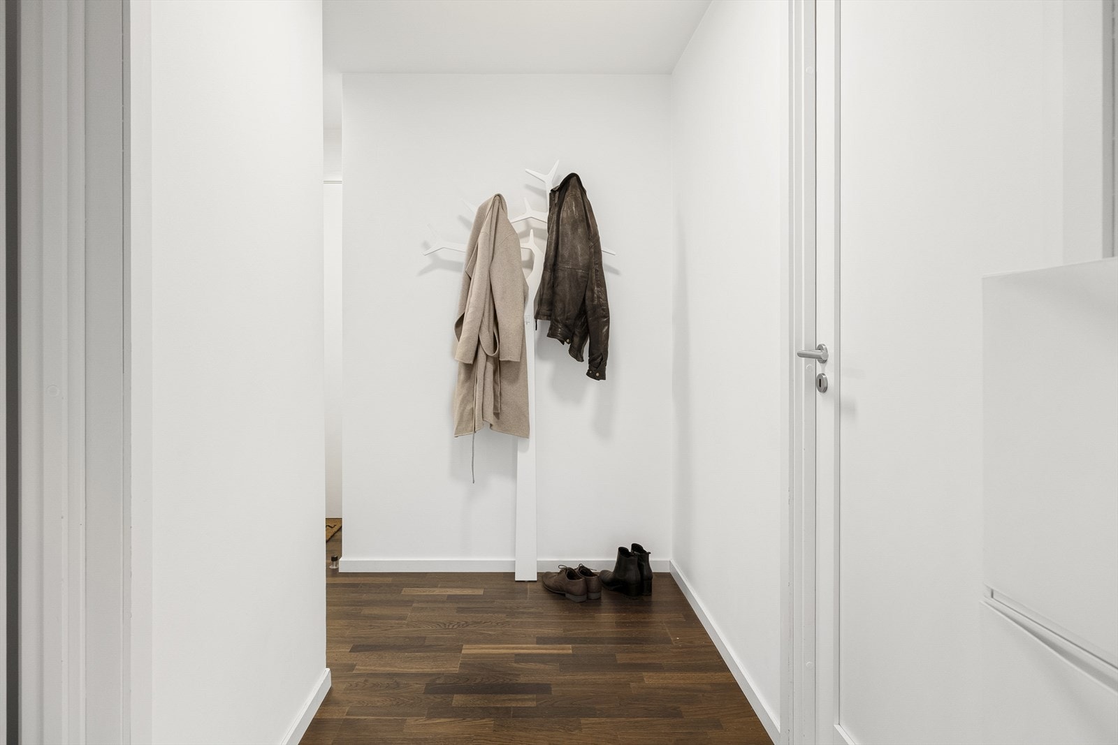 Fra inngangspartiet ønskes du velkommen inn i en lys entré med skoskap og knagger, en praktisk løsning som gir god plass til yttertøy og sko. Galleribilde