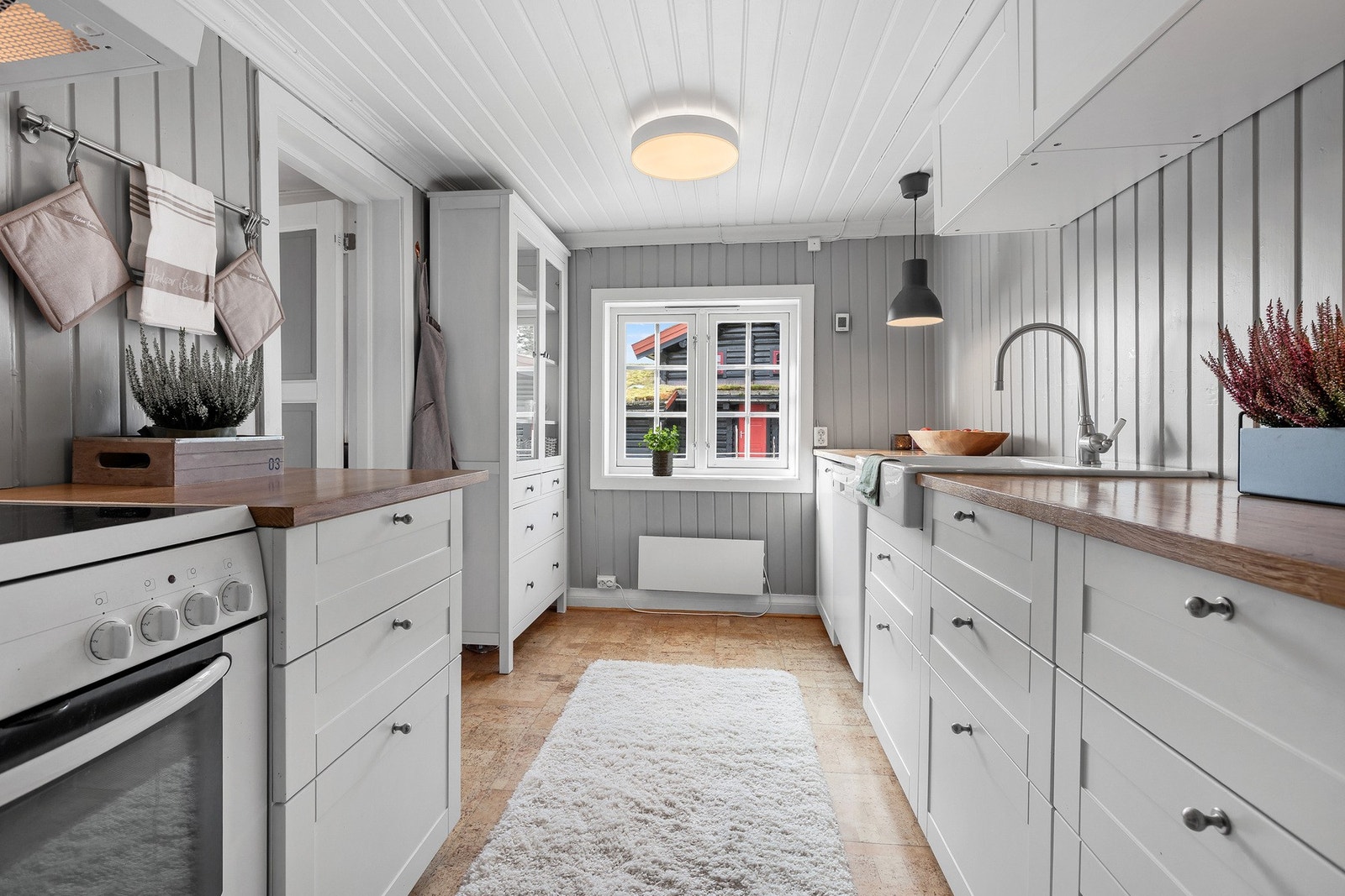 Kjøkkenet er innredet i en tidløs stil med lyse fronter og trebenkeplate, og gir rikelig med skap- og benkeplass. Galleribilde