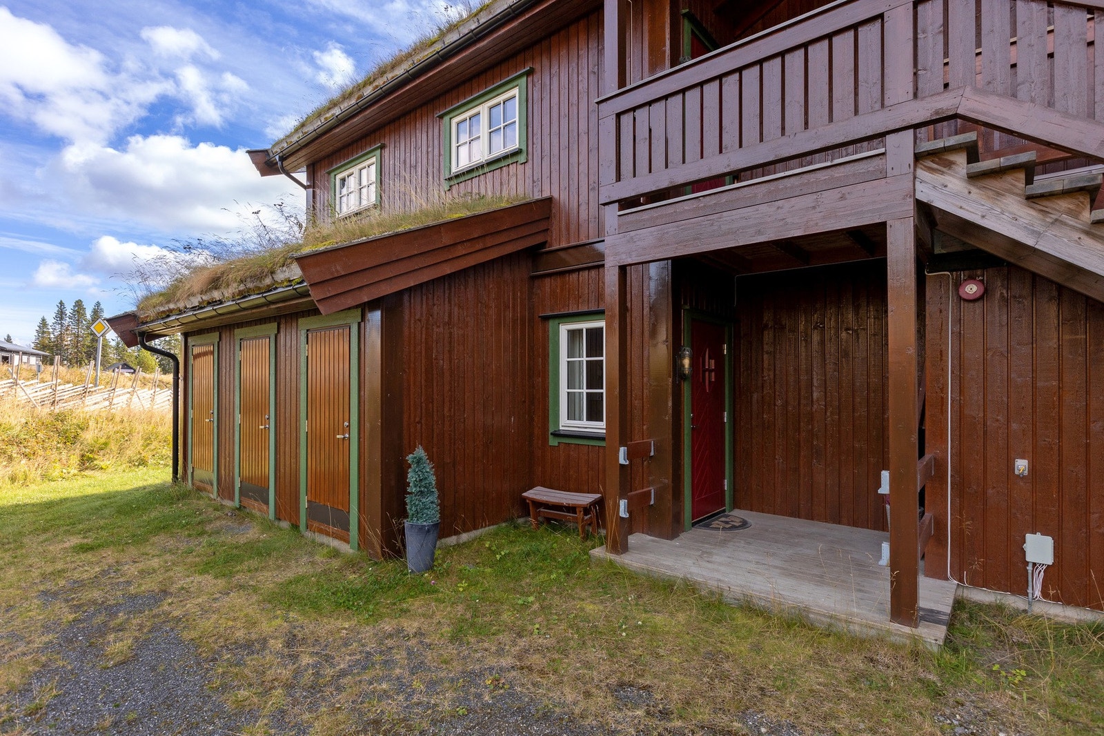 Takoverbygd inngangsparti med dør inn til en utvendig bod ved siden av. Galleribilde