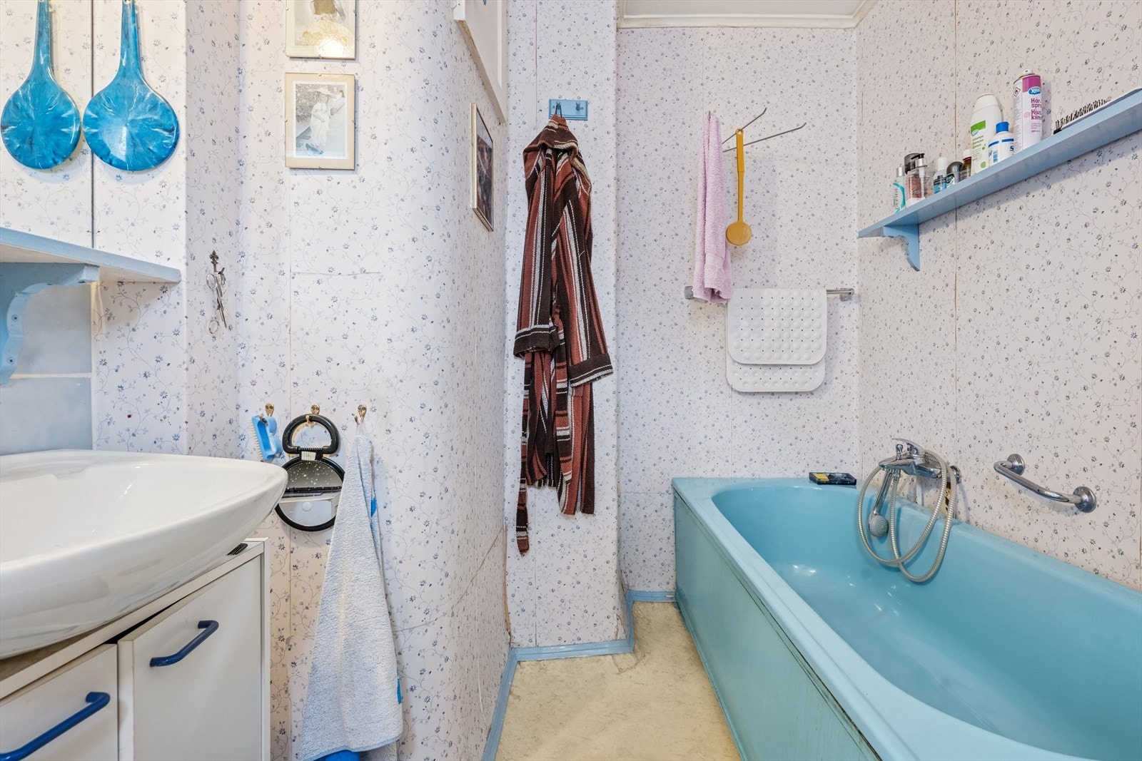 Baderommet er av eldre dato og har belegg av vinyl på gulvet. Rommet er utstyrt med servant i skapinnredning, badekar og ventilasjon i himling. Galleribilde