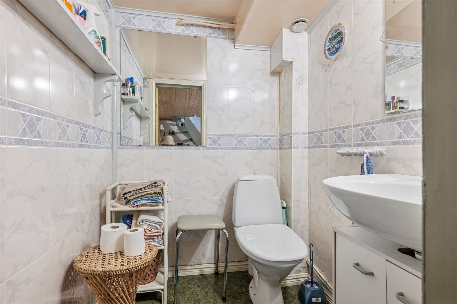 Toalettrommet er innredet med servant og toalett. Gulvet har vinylbelegg, og veggene er kledd med våtromsplater. Galleribilde