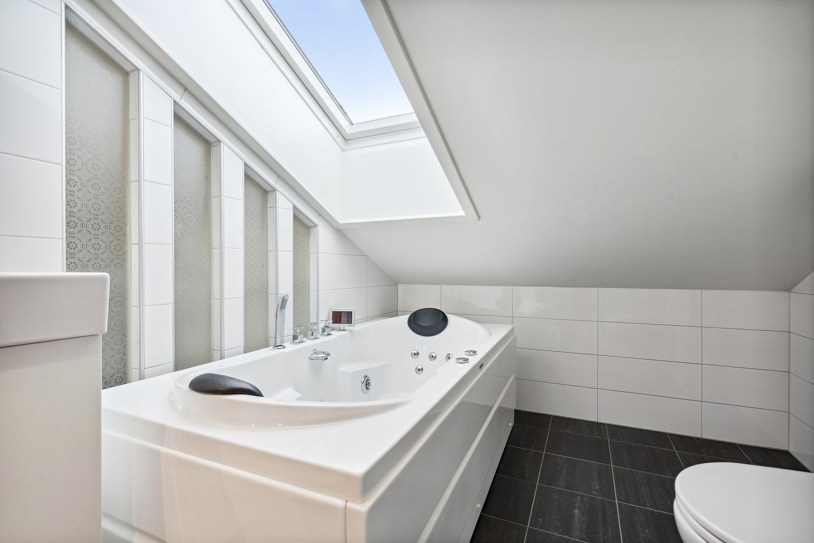 Hovedbadet er et lyst og pent flislagt bad - med badekar og vindu i himling Galleribilde