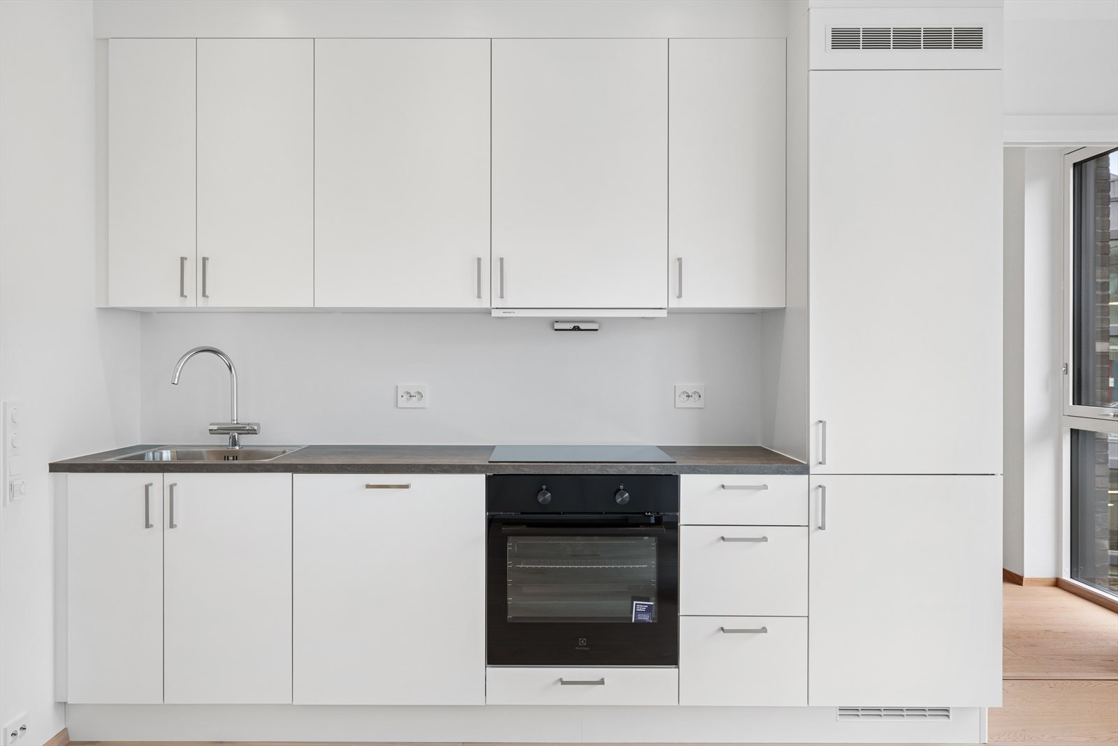 Moderne kjøkken med glatte fronter, nedfelt stålvask og platetopp - perfekt for matlaging. Galleribilde