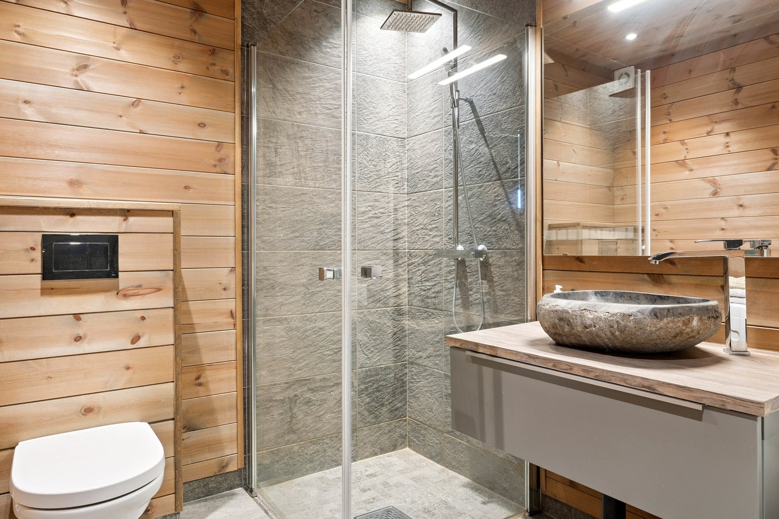 Dusjnisjen har flisbelagte vegger, beiset trepanel for øvrig på vegg og i himling. Vegghengt toalett, heltre skapinnredninger Galleribilde