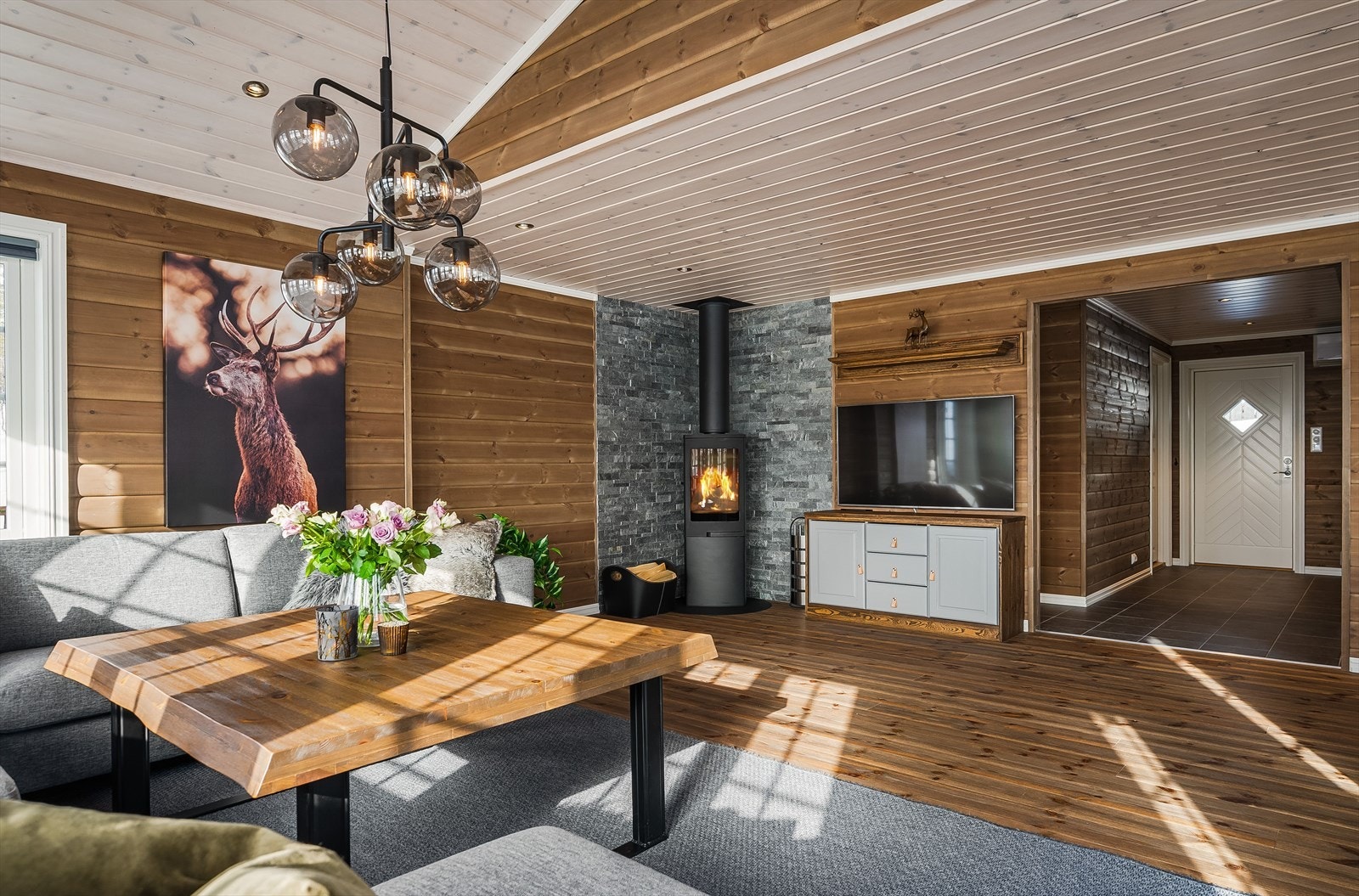 I hjørnet av stuen har du en moderne vedovn som både gir god varme og bidrar til ekstra hygge. Veggene bak ovnen er dekorert med flott fasadestein. Galleribilde