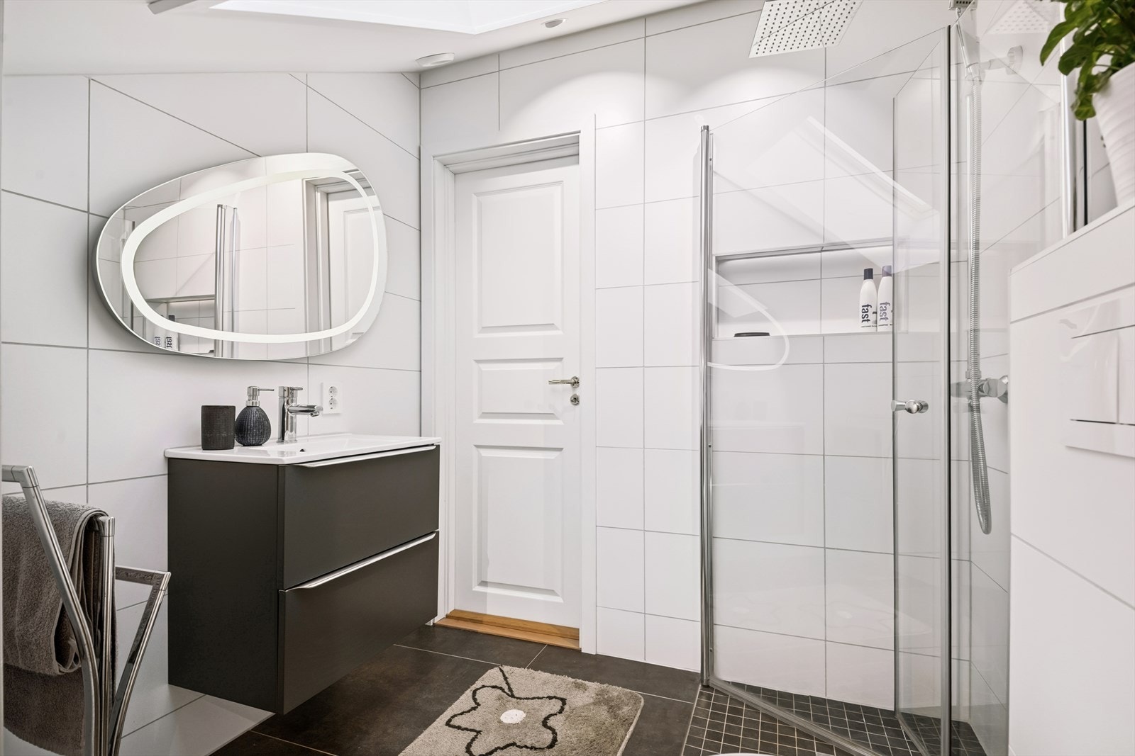 Baderommet er stilrent med moderne fliser, servant, skap og dusjkabinett Galleribilde