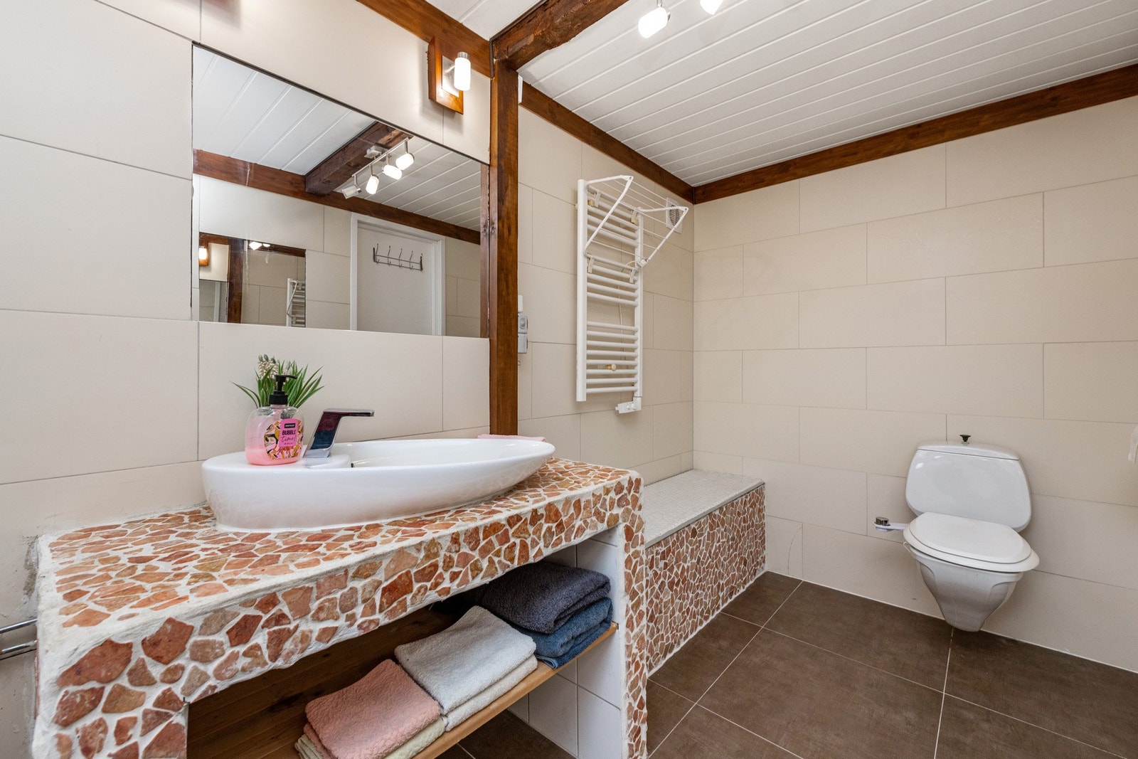 Baderommet er innredet med vegghengt toalett, badekar med dusjvegger og servant. Galleribilde