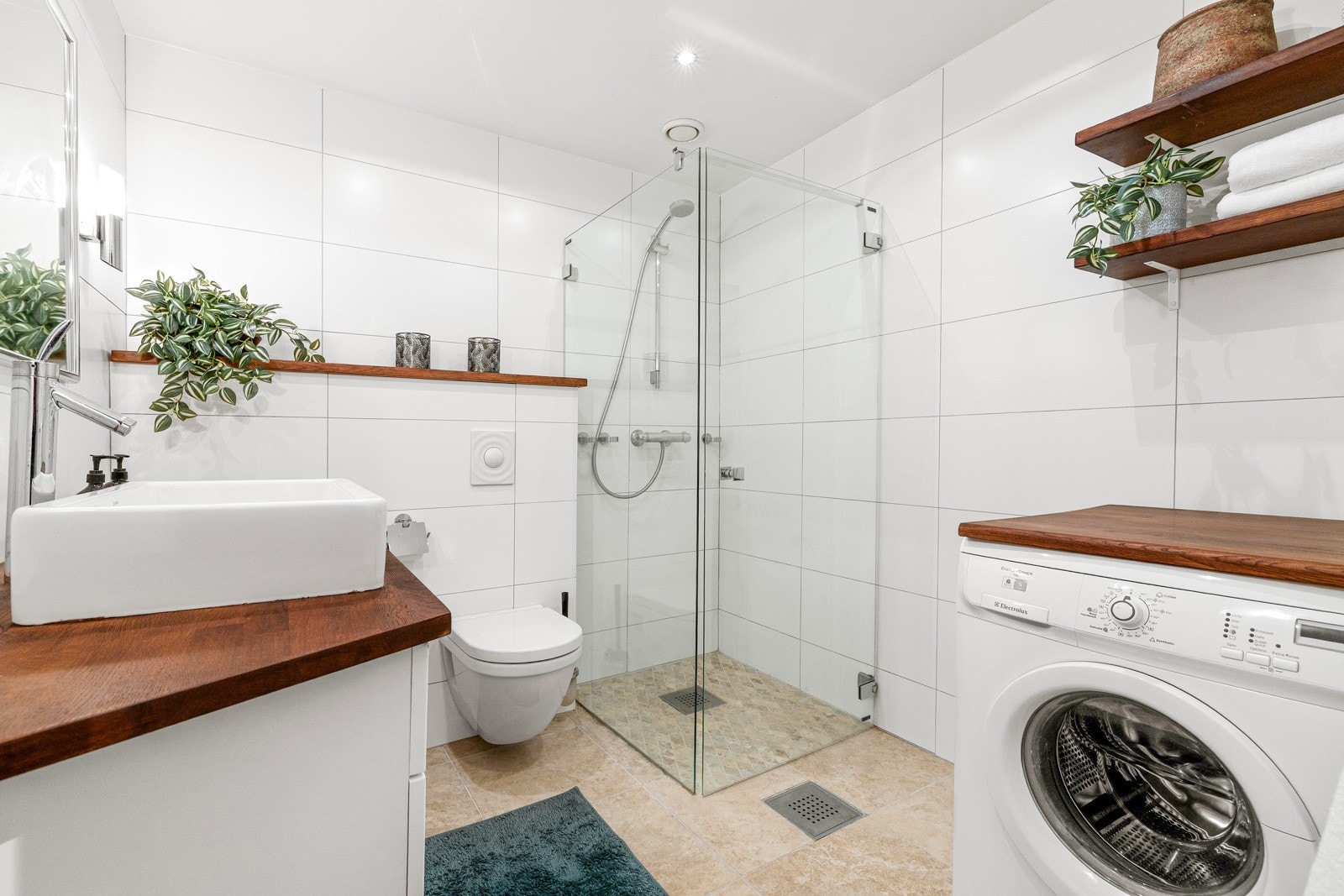 Flott bad som er innredet med dusjhjørne med glassdører, opplegg for vaskemaskin, vegghengt toalett samt servant med innredning og speil. Galleribilde