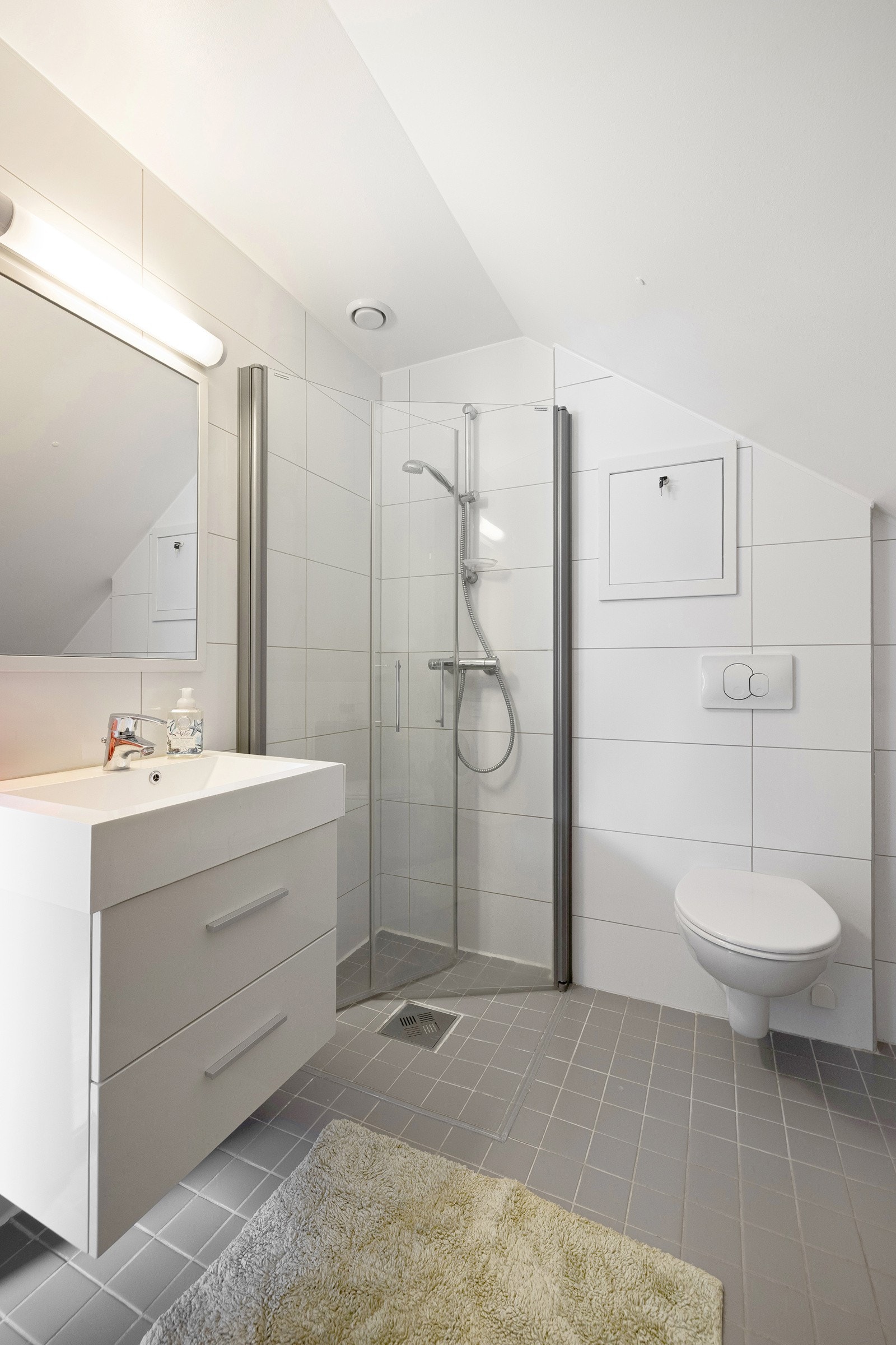 Romslig baderom med praktiske skuffer under servant som gir god oppbevaringsplass. Moderne opplyst speil over servant. Galleribilde