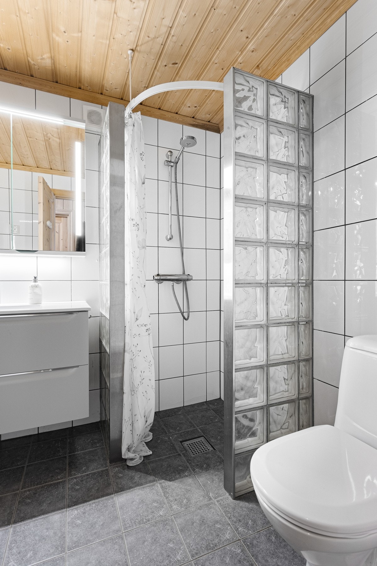 Baderom med toalett, dusjhjørne og innredning med servant Galleribilde