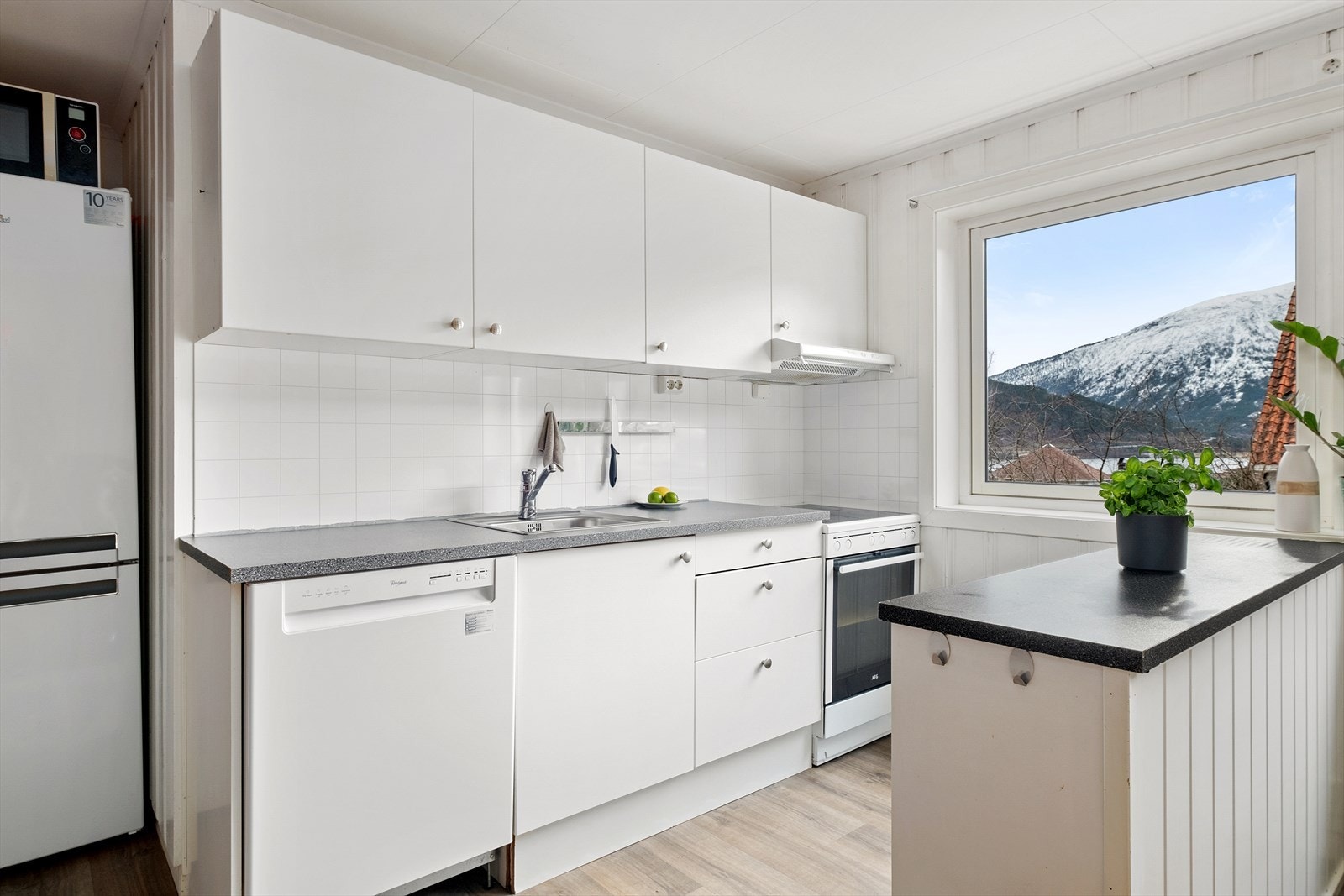 Kjøkkendelen har innreiing med glatte frontar. Kvitevarer som består av oppvaskmaskin, kjøleskåp og komfyr. Galleribilde