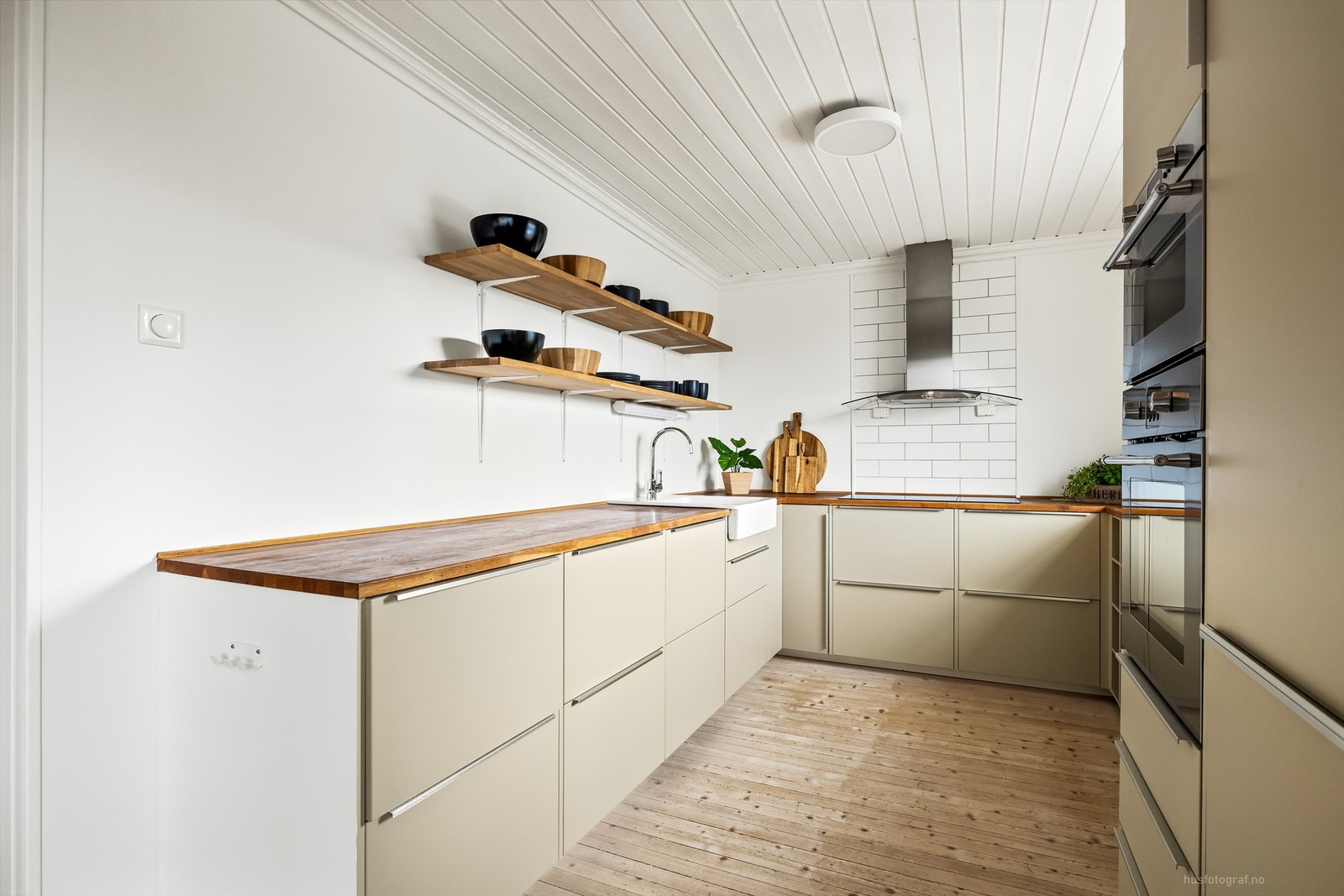 Pen kjøkkeninnredning med glatte fronter og benkeplate av heltre Galleribilde