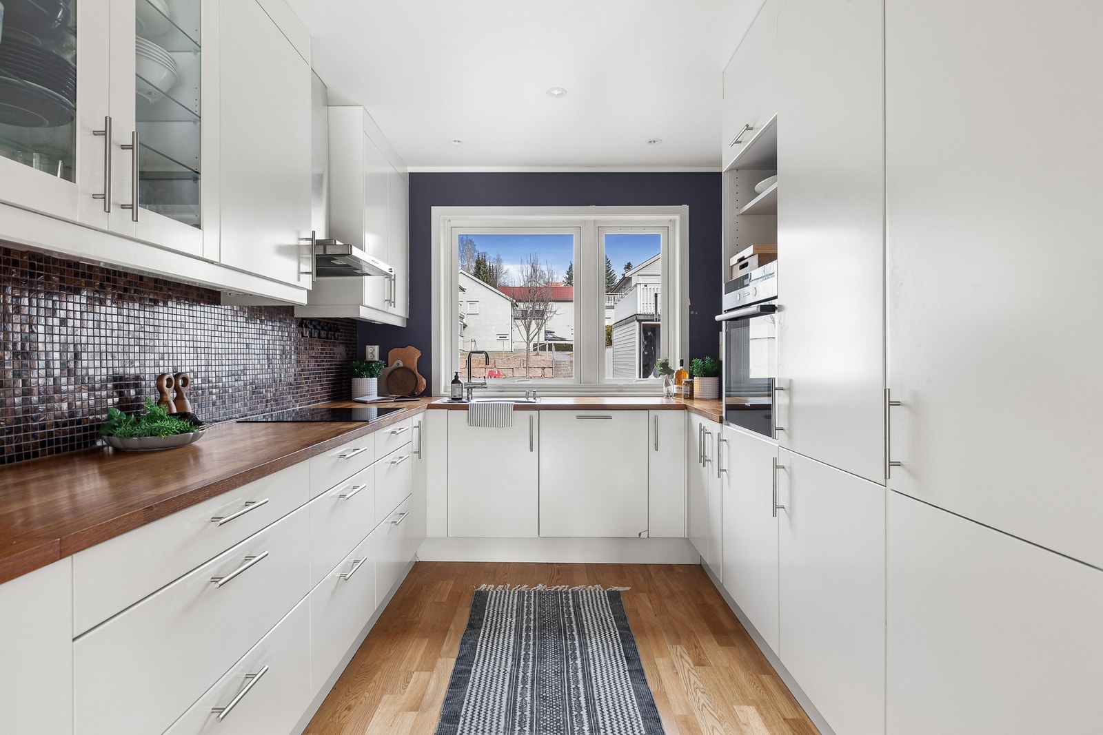 Et pent og innholdsrikt kjøkken som byr på gode oppbevaringsmuligheter og arbeidsplass med en stor benkeplate. Galleribilde