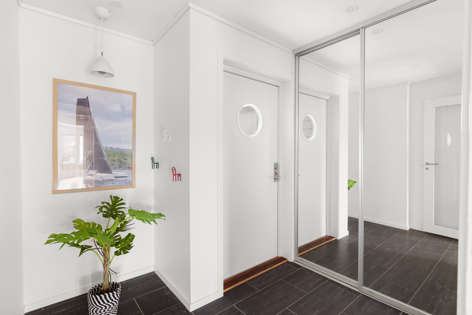 Lys, trivelig og flislagt entré med skyvedørsgarderobe i speil. Galleribilde